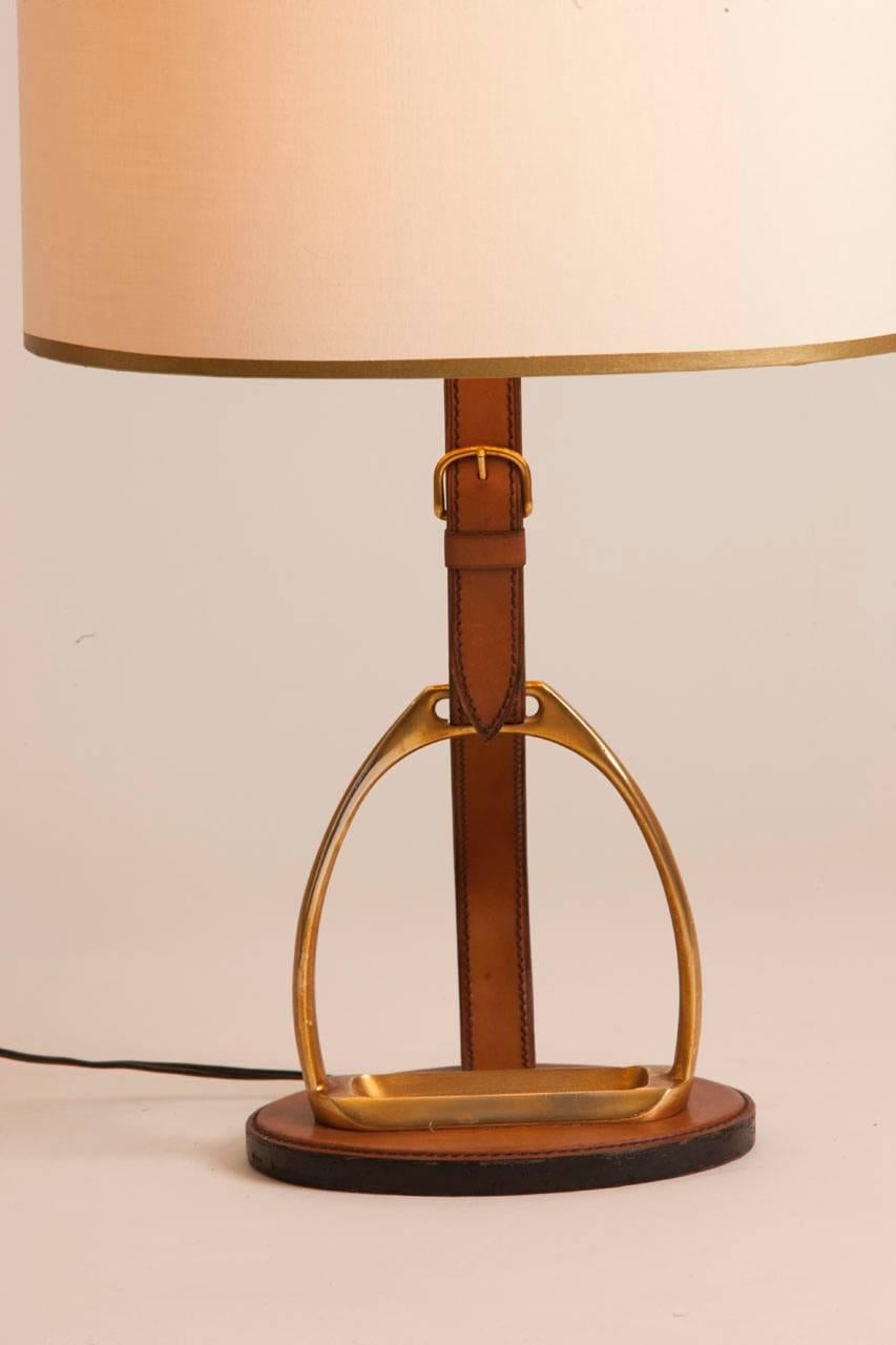 French leather and brass table lamp stamped Longchamp. Lamp features equestrian motif with leather and brass stirrup and buckle. Custom shade made in Paris.