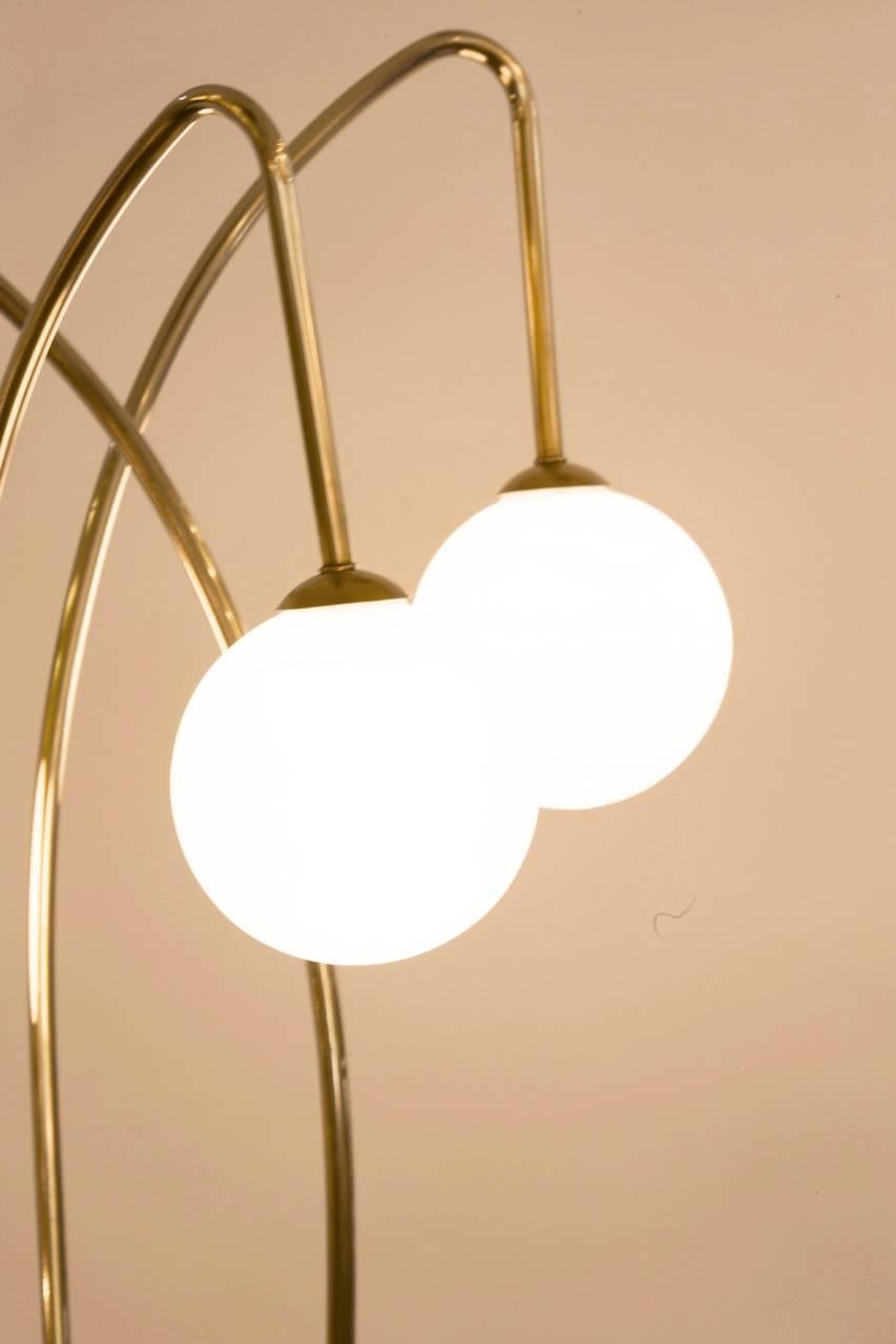 Mid-Century French brass floor lamp featuring three illuminated frosted glass globes as the end of each arm. The arms elegantly curve to differing heights. Lamp has been completely rewired for the United States.
