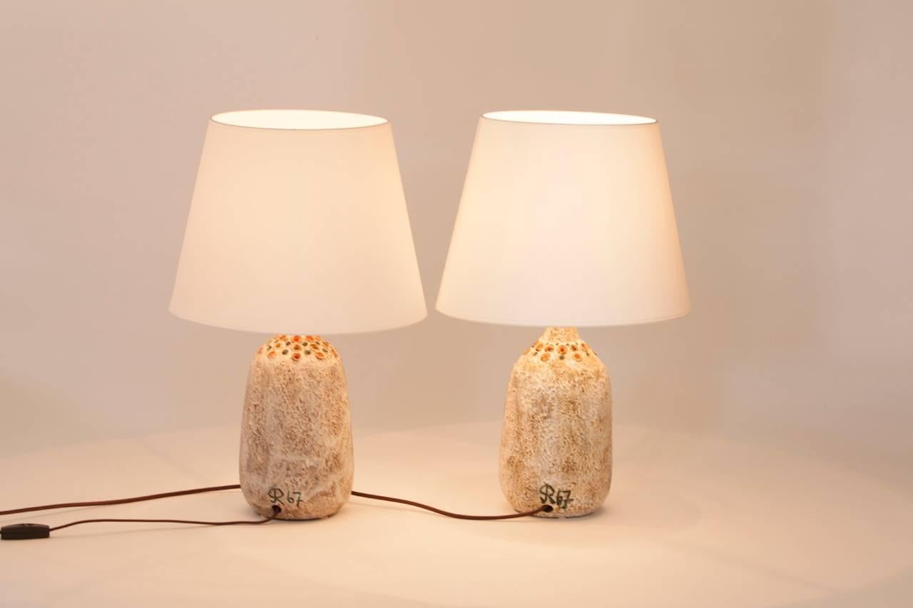 Pair of French ceramic table lamps signed and stamped 1967 by Raphael Giarusso. Lamps feature custom shades made in Paris.