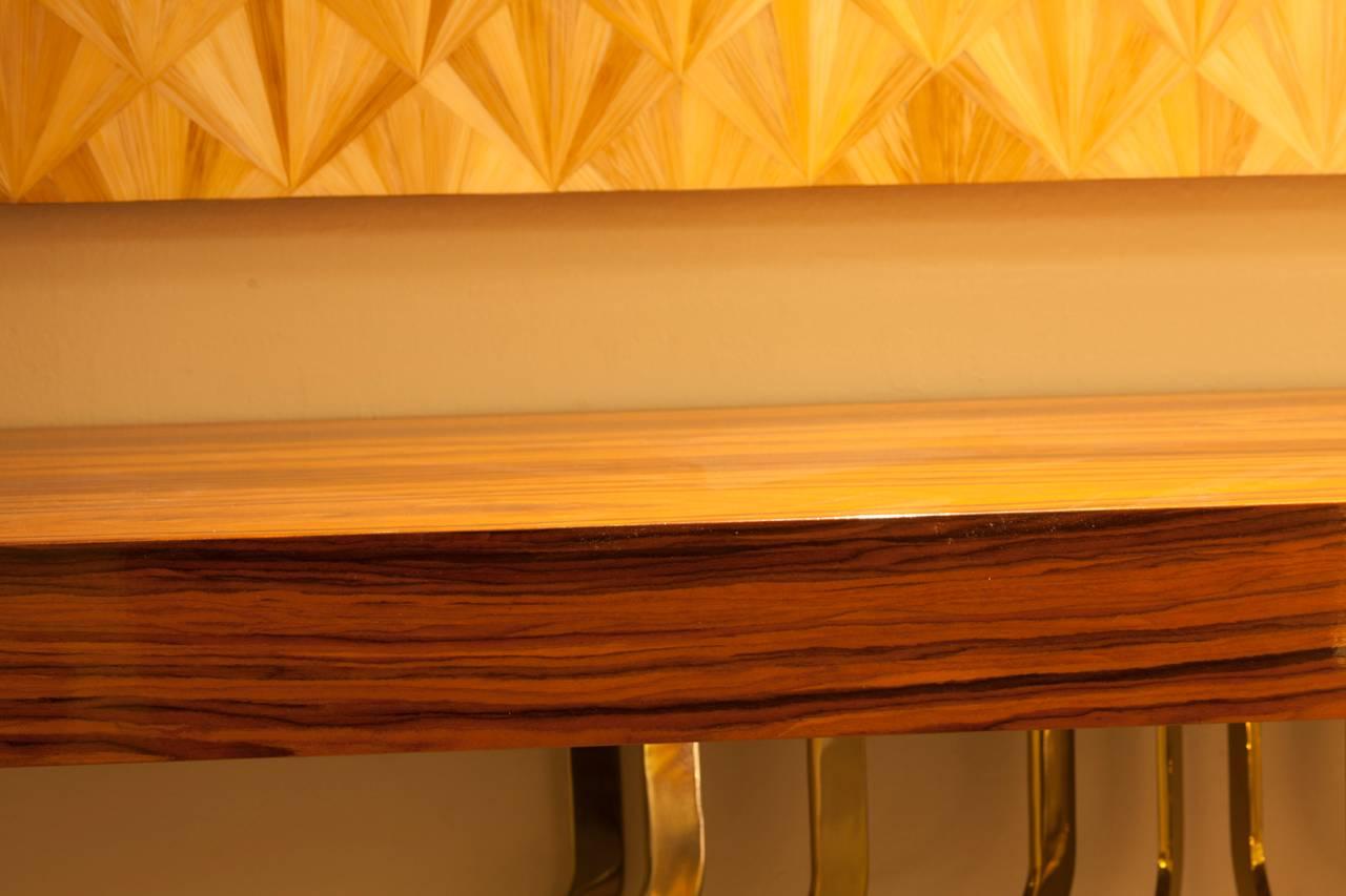 Italian console in lacquered Madagascar wood featuring curved brass legs. Console is affixed to wall for installation allowing for varying heights.