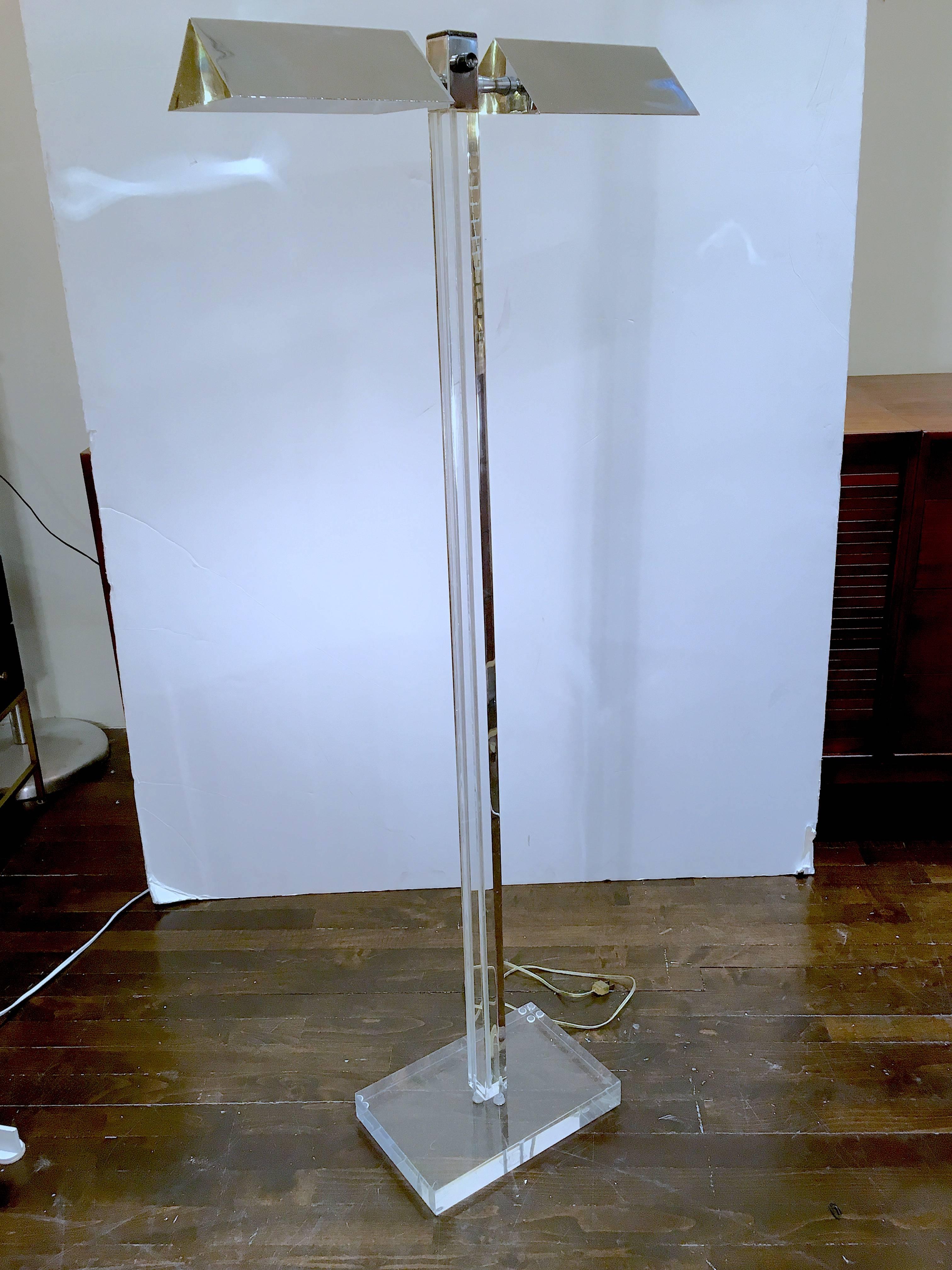 Stylish Lucite floor lamp by George Kovacs. The lamp has a pair of light bulbs, each covered by adjustable chrome shades. The width of the lamp is 21 inches at the chrome shades. The depth of the lamp is 8 inches at the Lucite base. Please contact