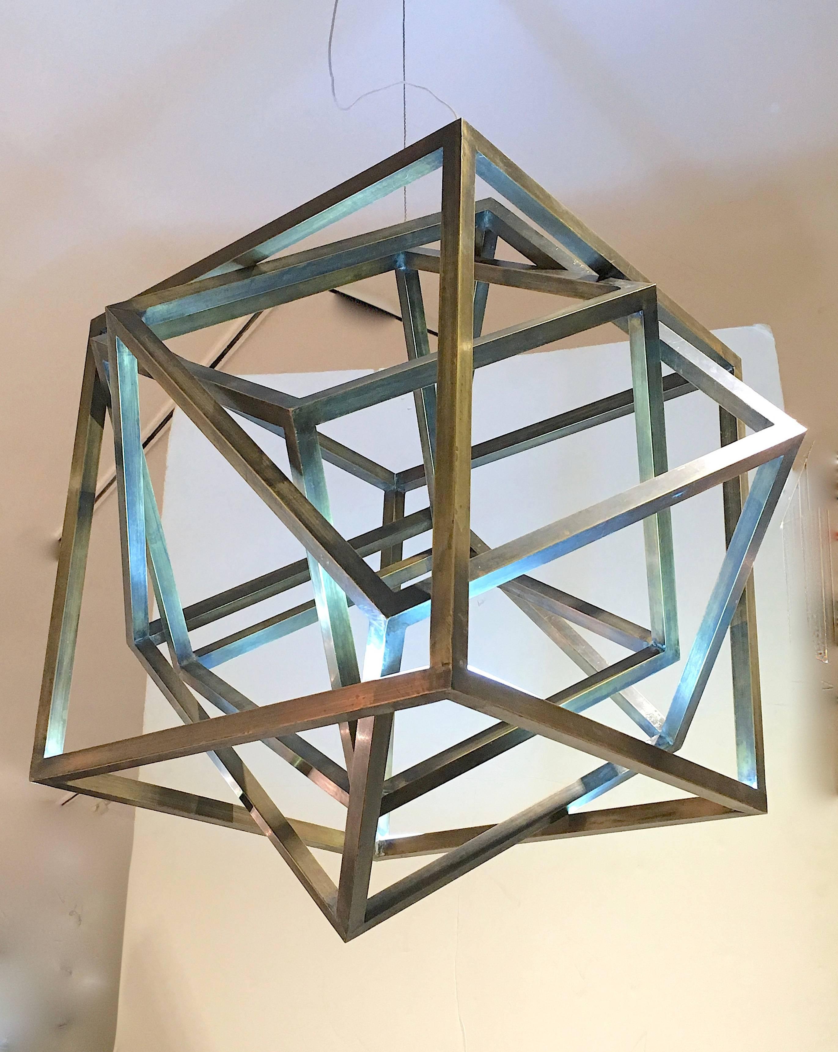 Striking architecturally designed chandelier composed of a number of brass finished square cubing elements entirely interlocked. The light fixture is in a versatile scale. The pendant is finished in bronzed, patinated brass and is illuminated by
