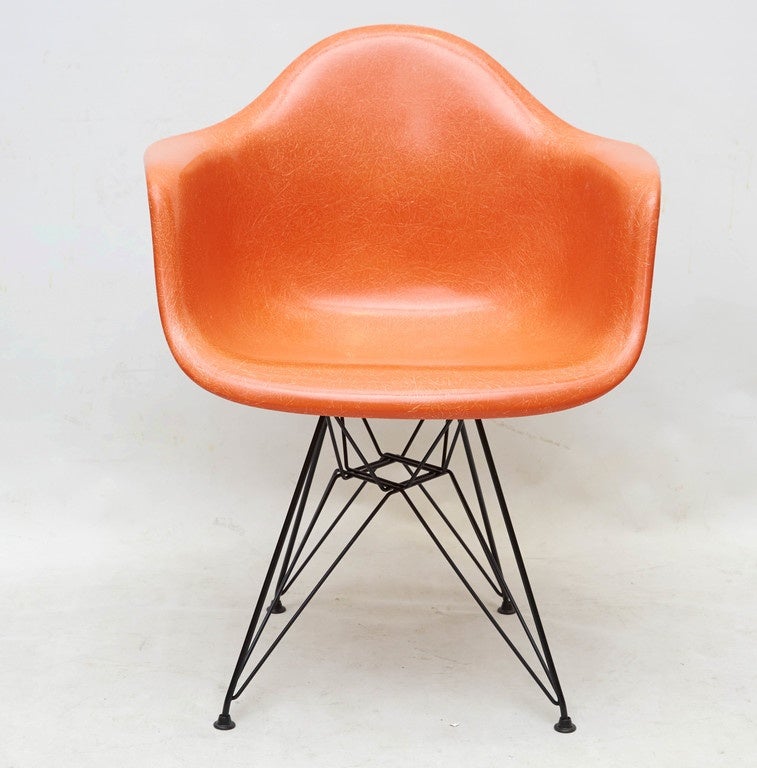 Pair of iconic Charles Eames arm shell lounge chairs in a bold orange with nice fiberglass graining. A design Classic in a statement color that is remarkably comfortable. Please contact for location.