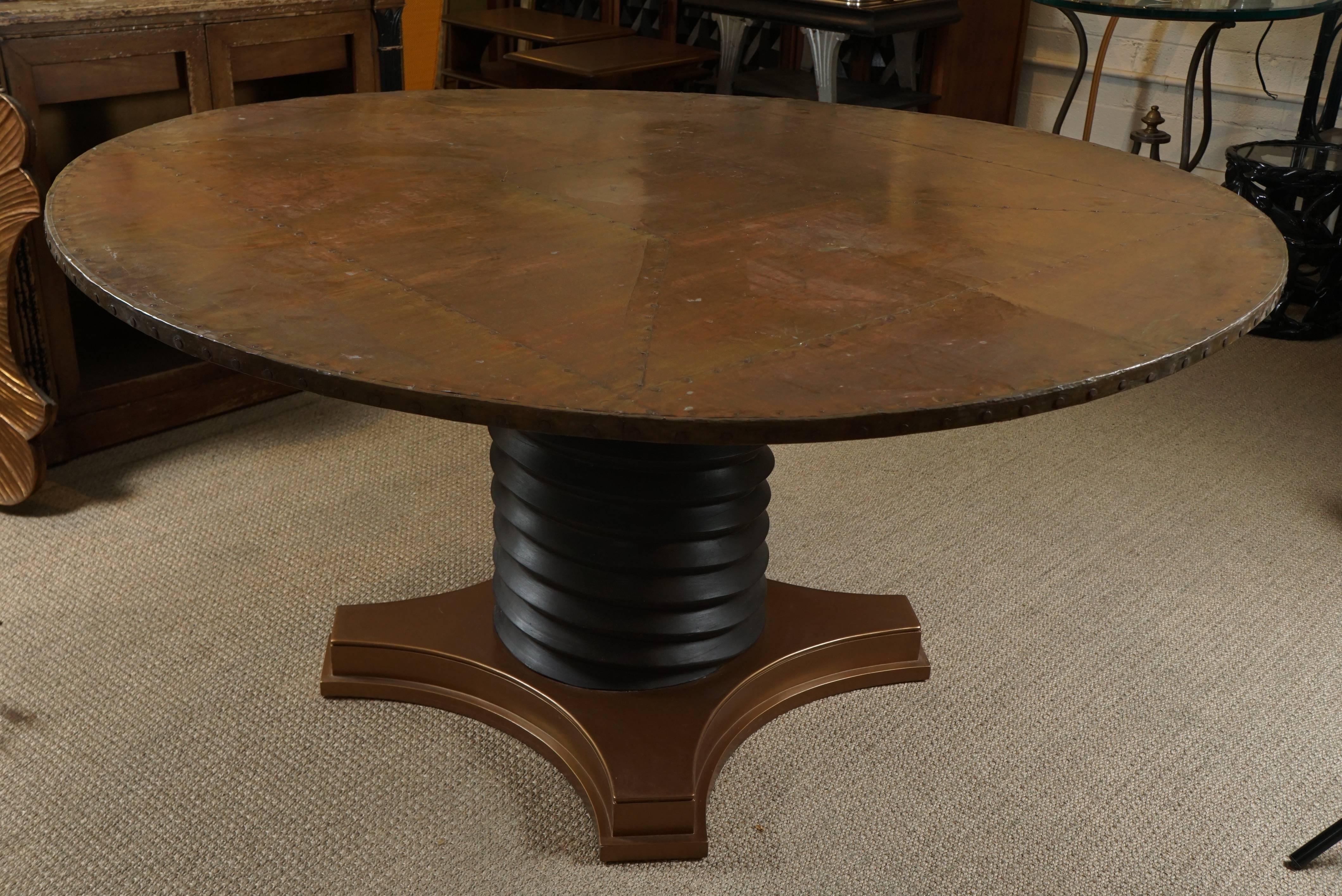 Here is a great round dining table with a copper top with hammered nail detail. The pedestal base has a spiral motif in a graphite black lacquered finish that rests on a painted metallic copper base. The table has a Brutalist style with a