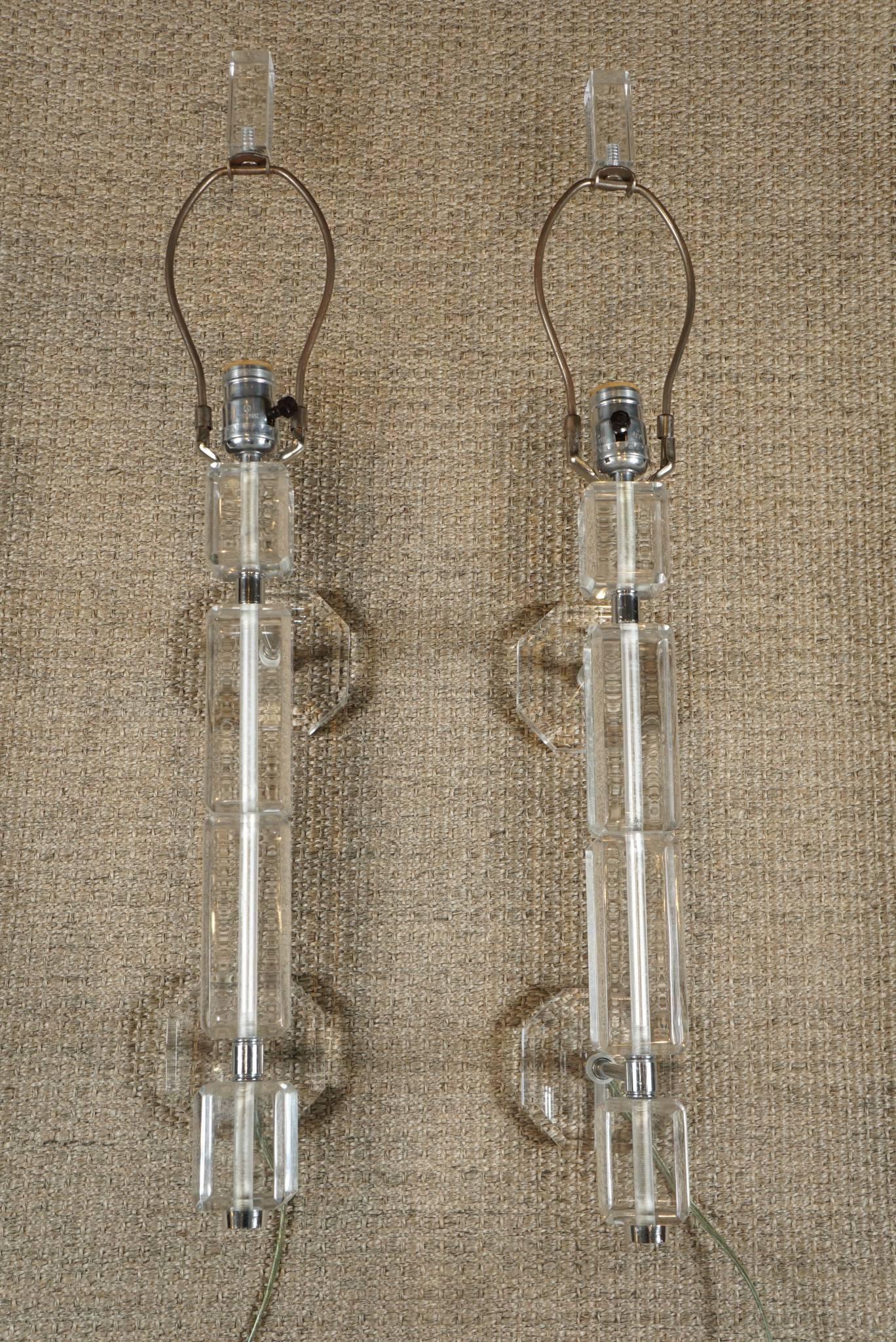 Here is a pair of elongated Lucite wall sconces. The lamps are wired to plug in but can be modified for a wall socket. There are built in brackets to attach to the wall. The lamps have harps and finials for shades and take standard light bulbs.
The