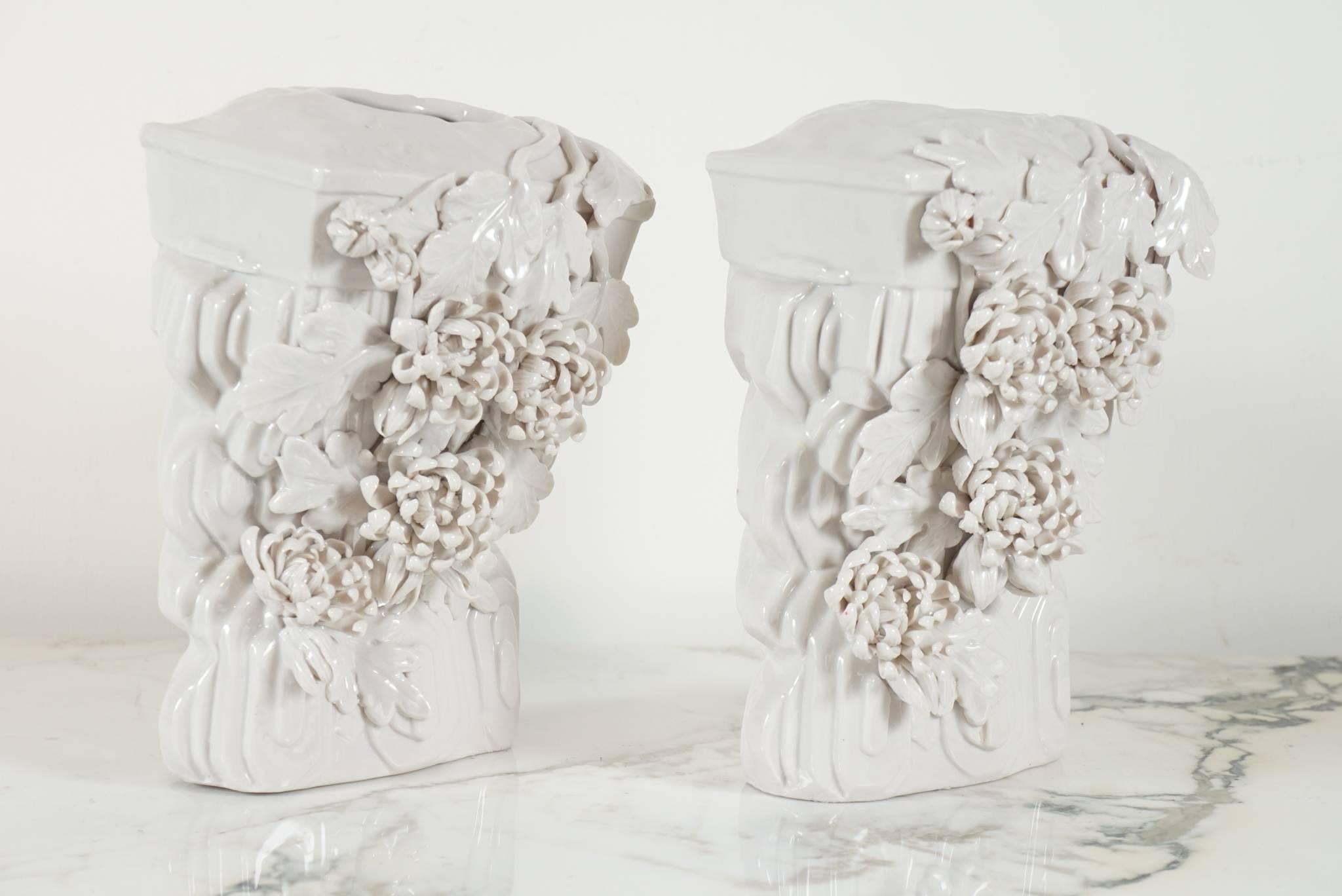 Here is a beautiful pair of blanc de chine vases that are also wall brackets.
The pieces are intricately detailed with flowers and leaves and architectural detail in an Art Deco style. The vases have full surround detail with more embellishment on
