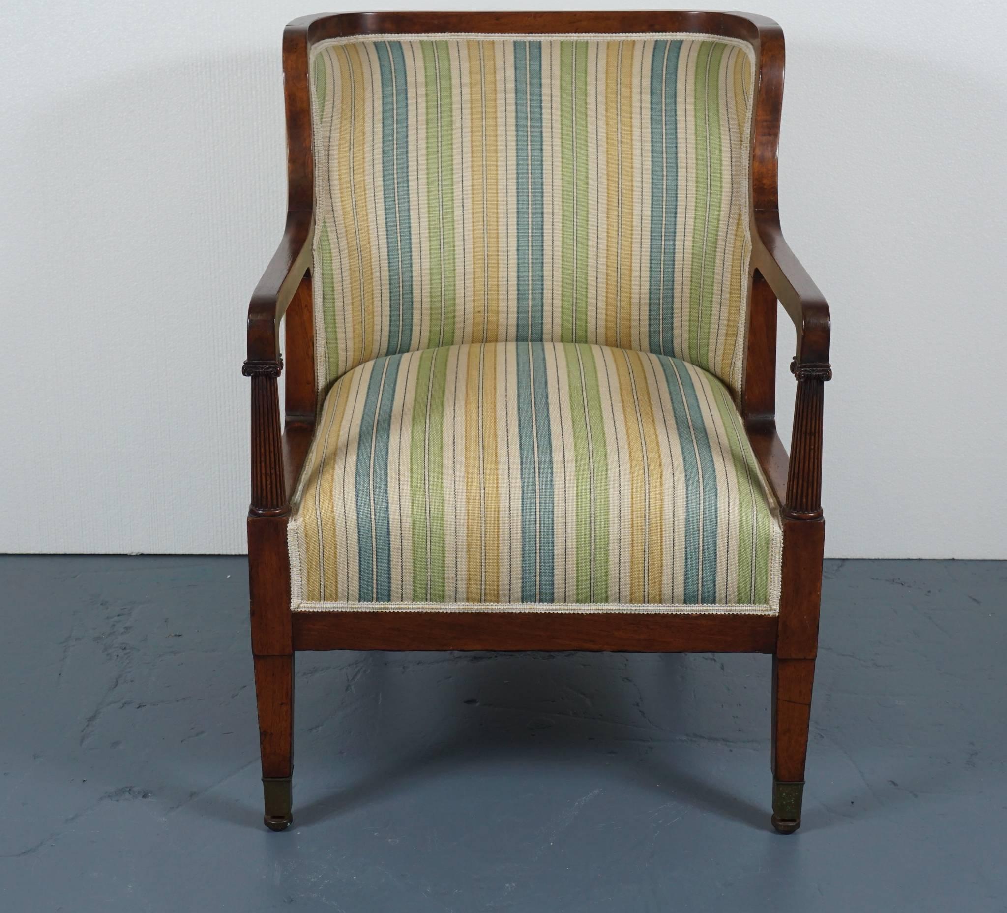 Here is a beautiful Empire arm chair in mahogany with a barrel back motif.
The chair features reeded column arms and a heavy linen fabric with striping.