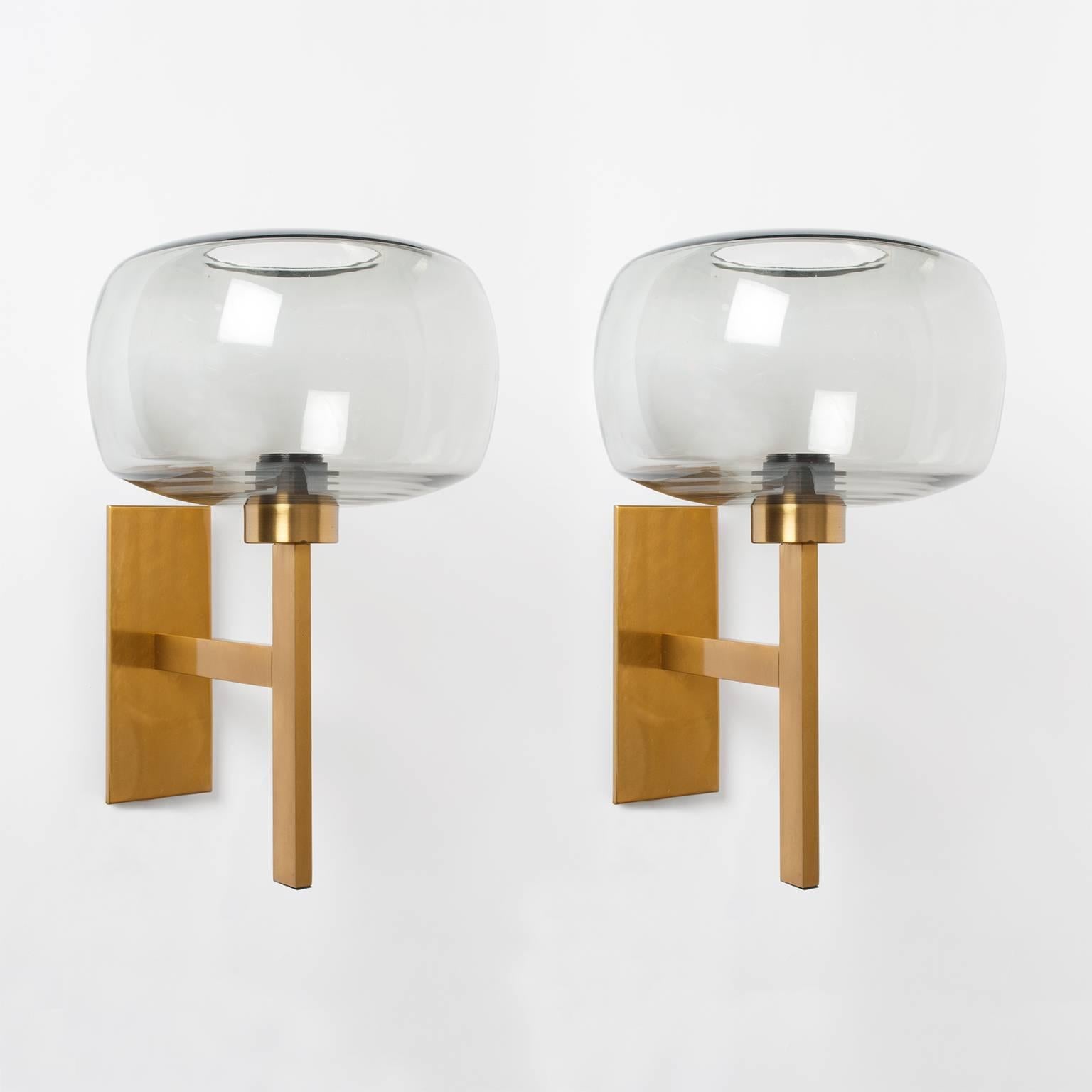 A large pair of Scandinavian Modern Westal Bankeryd polished and lacquered brass sconces with gray glass shades. Each sconce has a single arm with extends from a rectangular brass back plate. Newly wired with single Edison sockets for use in the