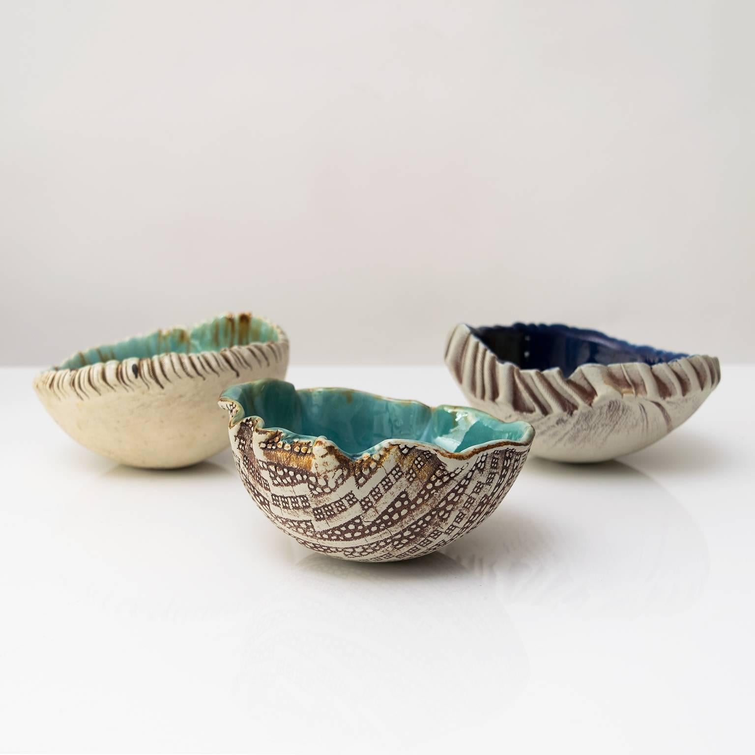Three unique Scandinavian Modern hand built and glazed bowls by artist Bengt Berglund for Gustavsberg studio 1960-1977. The exterior of the bowls are partially glazed while the interiors are pale to dark blue-greens and yellow-greens glazes.
