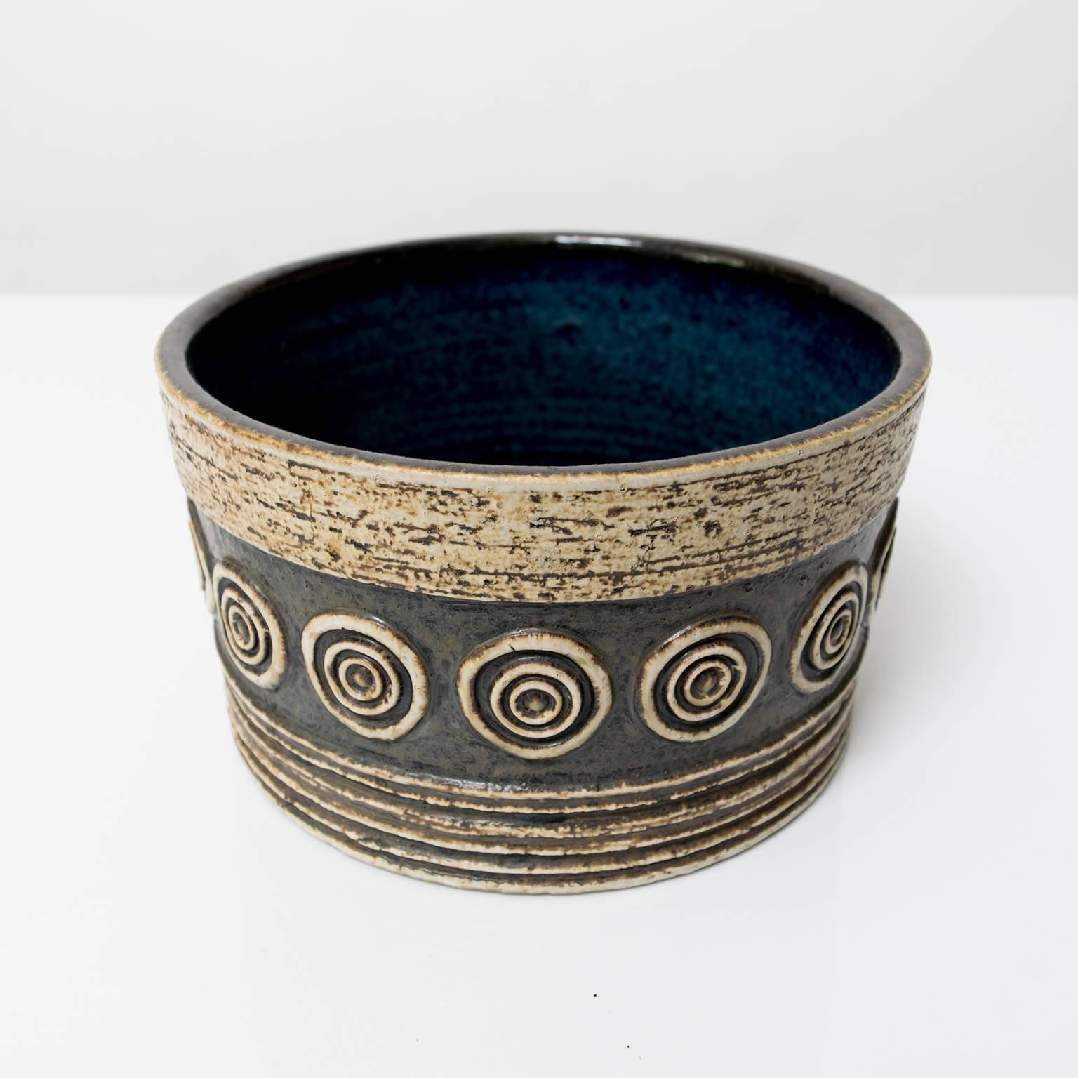 A Scandinavian Modern studio bowl by Britt-Louise Sundell for Gustavsberg, circa 1960. This piece is highly textured with horizontal grooves, circles and glazed in earthy, neutral colors and a deep blue inside.
Measures:
Height: