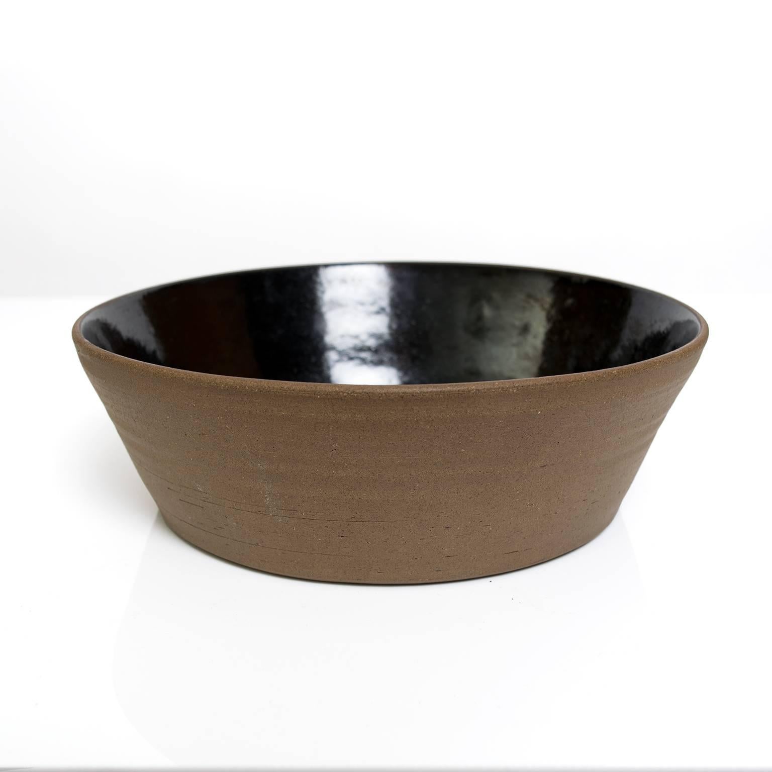 Scandinavian Modern ceramic studio bowl by designer Signe Persson-Melin. The exterior is unglazed in a dark brown clay while the interior has a shiny black glaze.
Measures:
Height: 3.5