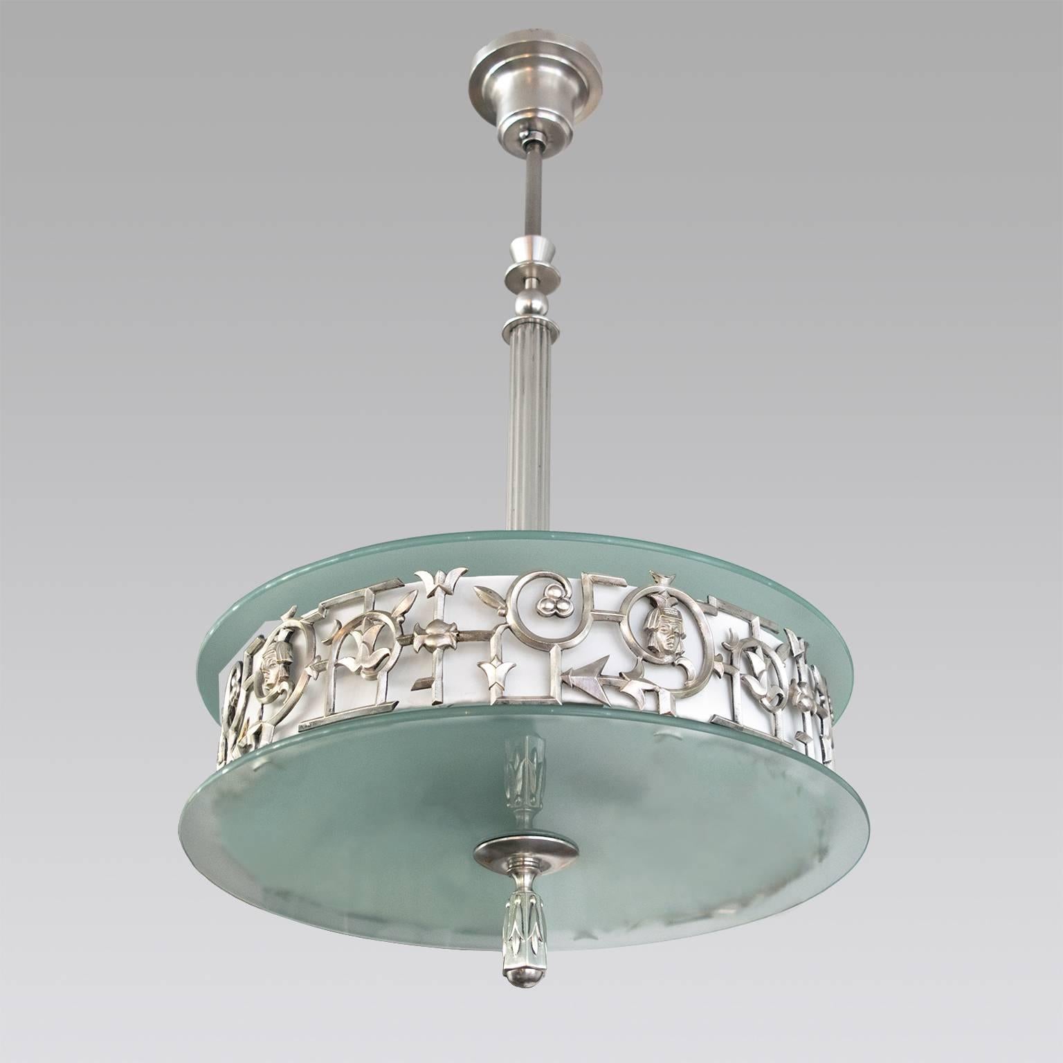 An elegant Scandinavian Modern, Swedish Art Deco (Swedish Grace) pendant with silver plate grillwork, stem, canopy and finial. The grillwork has stylized flowers and vines and face with an Egyptian headdress. Two sand-blasted pieces of glass diffuse