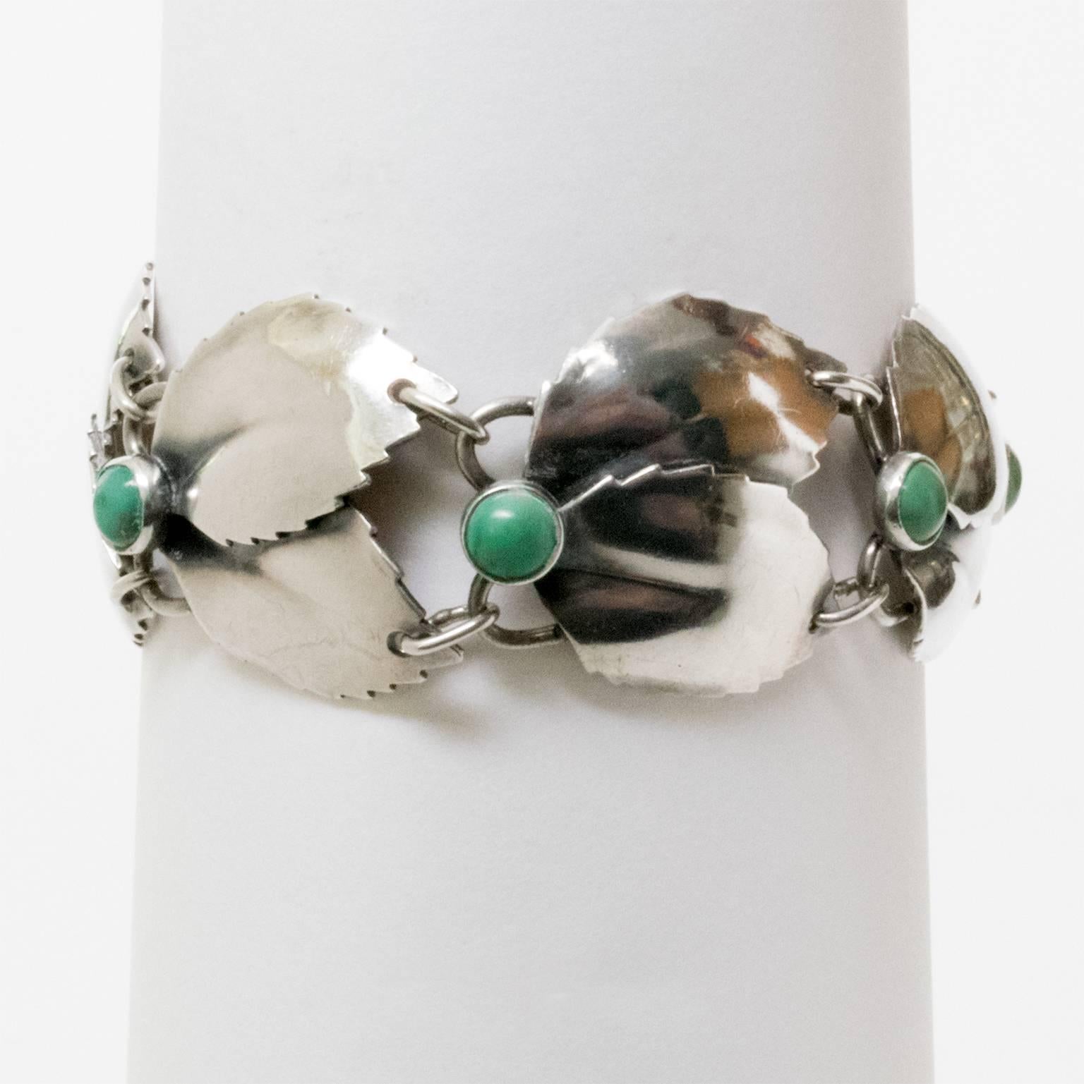 A Scandinavian Modern silver bracelet with linked overlapping leaves detailed with malachite cabochons. Designed by Gertrud Engel for A. Michelsen, 1950s, Stockholm, Sweden.
Diameter: 2.5".
Height: 1".