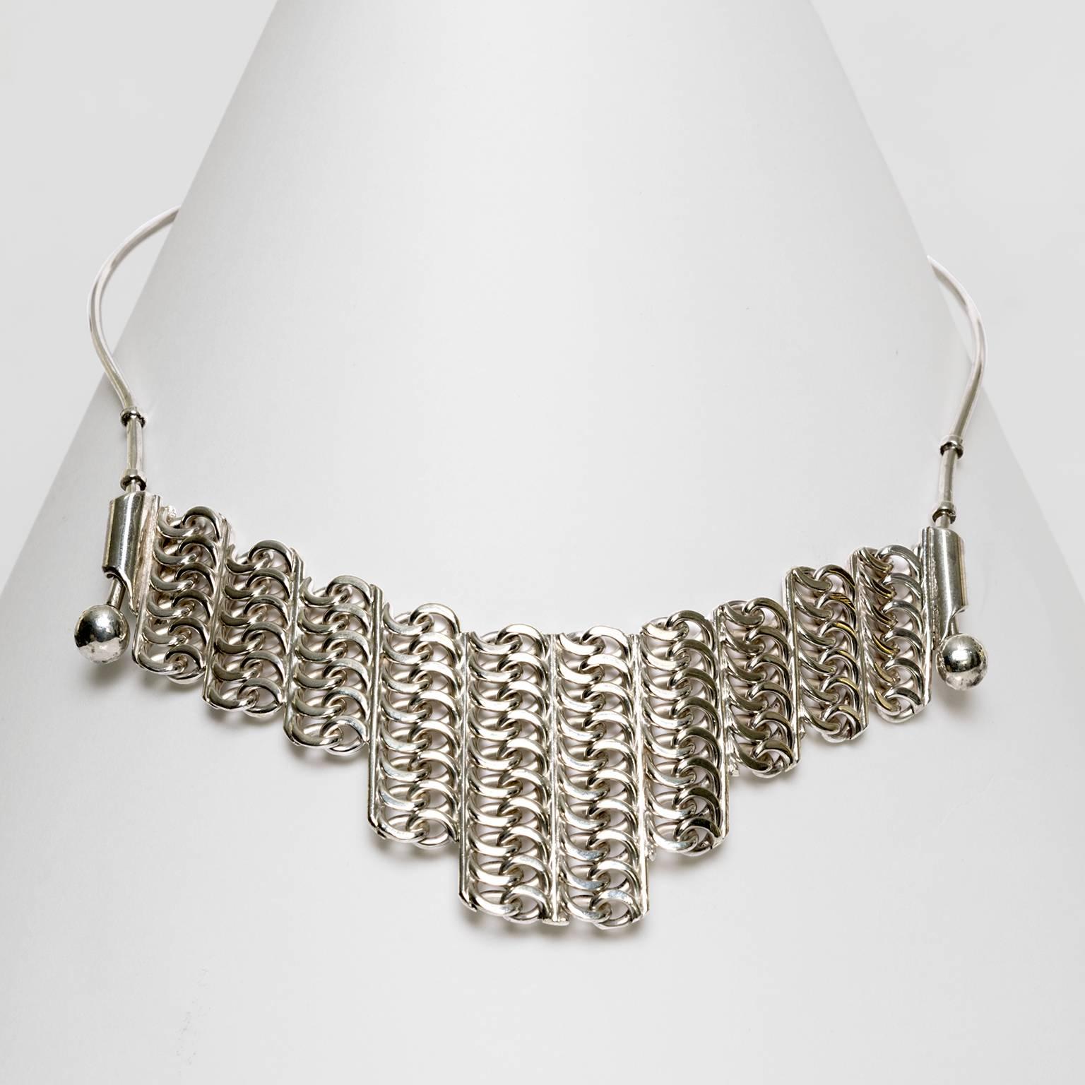 A Scandinavian Modern sterling silver necklace with adjustable panel. Made by S.G. Hellstrom, Gnesta, Sweden, 1965.
 
Measures: Opening diameter: 5" x 5".
Overall height: 6.5".