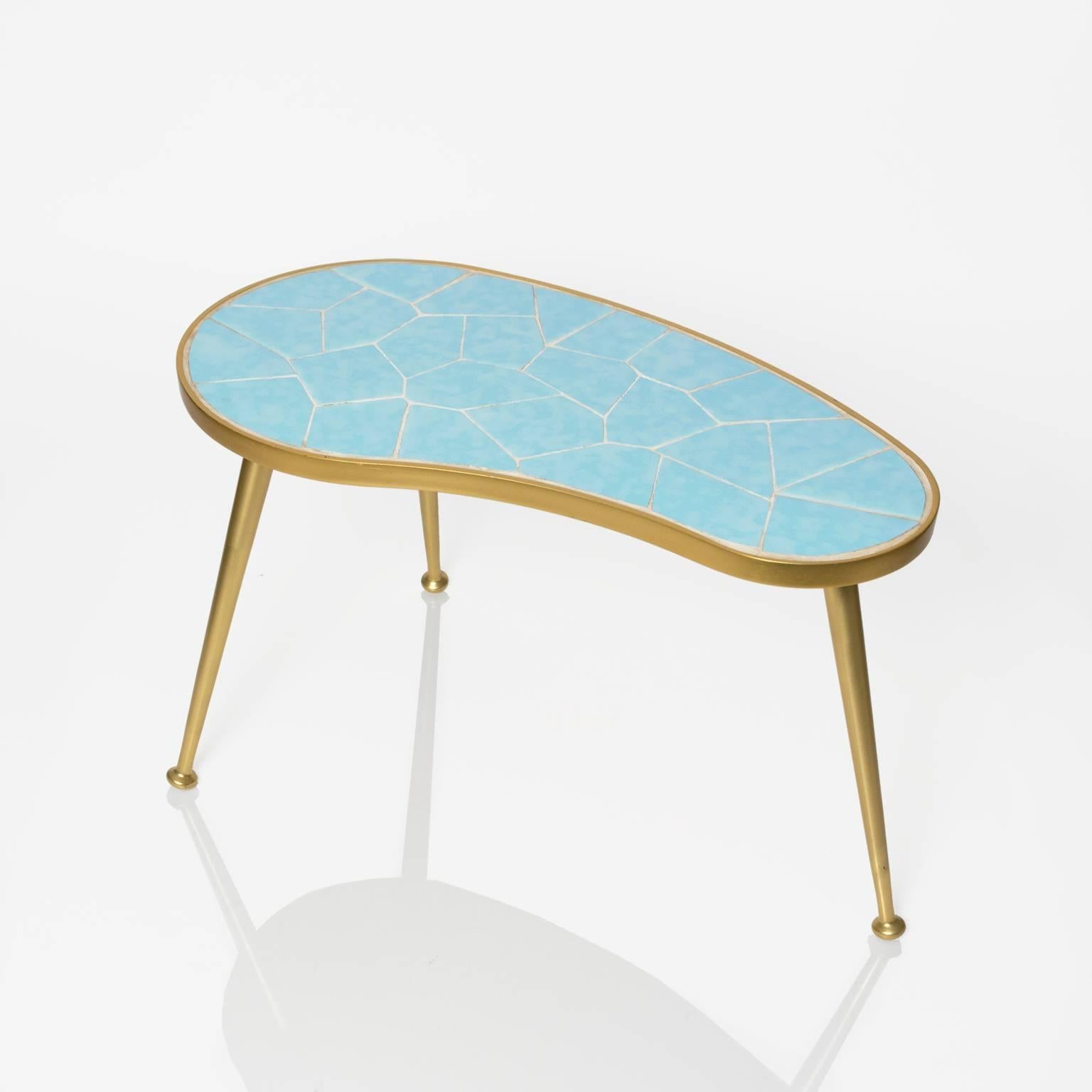 A small organic kidney shaped occasional table with a blue tiled surface. The frame and three legs are cast anodized aluminum in gold. Made in Europe, circa 1970s.
 
Measures: Width 11”, length 19.5”, height 11".