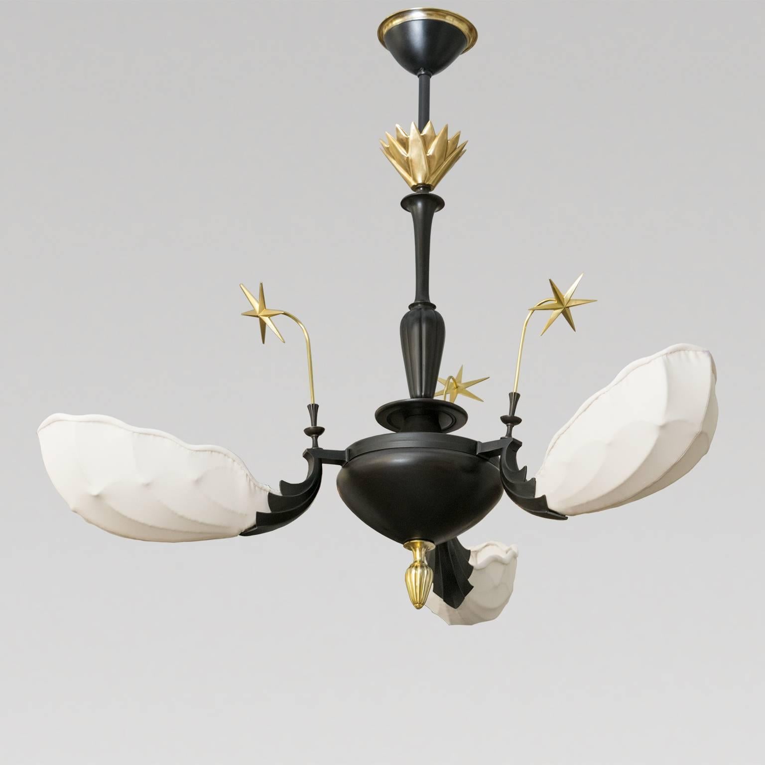 A very special Scandinavian Modern, Swedish grace pendant light with a deeply patinated brass frame detailed with polish brass elements which include stars, a finial and crown. Each of the three arms holds a shell form shade newly covered in an