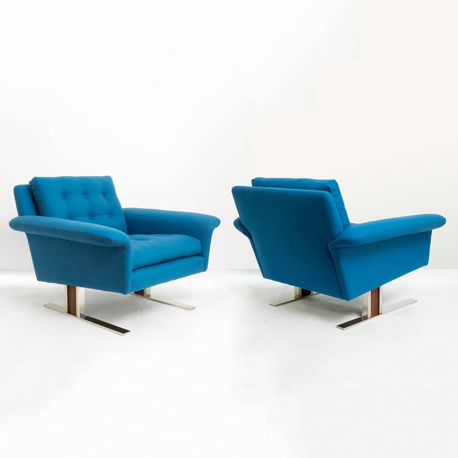 A pair of roomy, stylish and very comfortable Scandinavian Modern armchairs. Newly upholstered in azure blue 100% wool fabric with seat and back cushions detailed with buttons. Legs are solid polished steel with an insert of Rosewood. Designed by