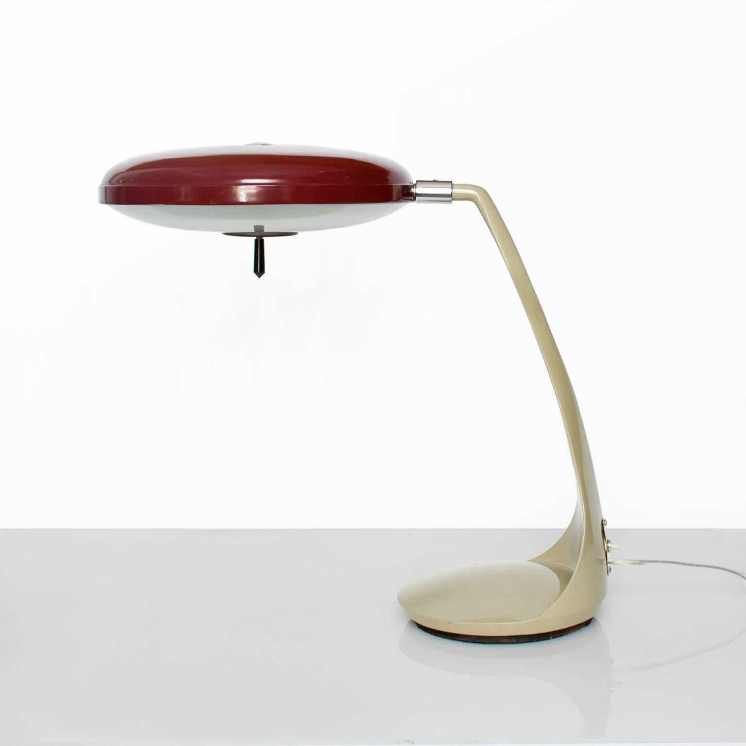 A Spanish Mid-Century Modern Lupela desk lamp in cast iron, steel and glass. This is a rare red shade model. The sculpted body is a neutral gray green, all paint is original. The shade is adjustable and the lamp sits on a rotating base. New wired