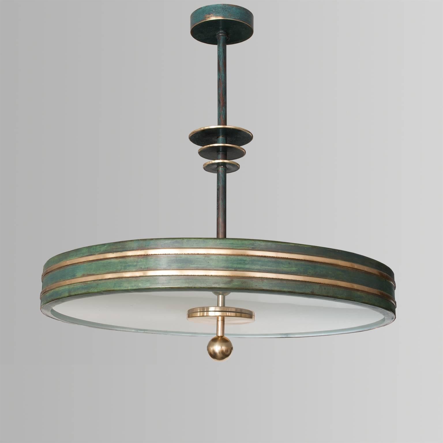 A Scandinavian Modern disk shaped pendant with polished and patinated brass body. The stem is decorated with 3 disks of varying sizes. The patinated brass canopy has a diameter of 4