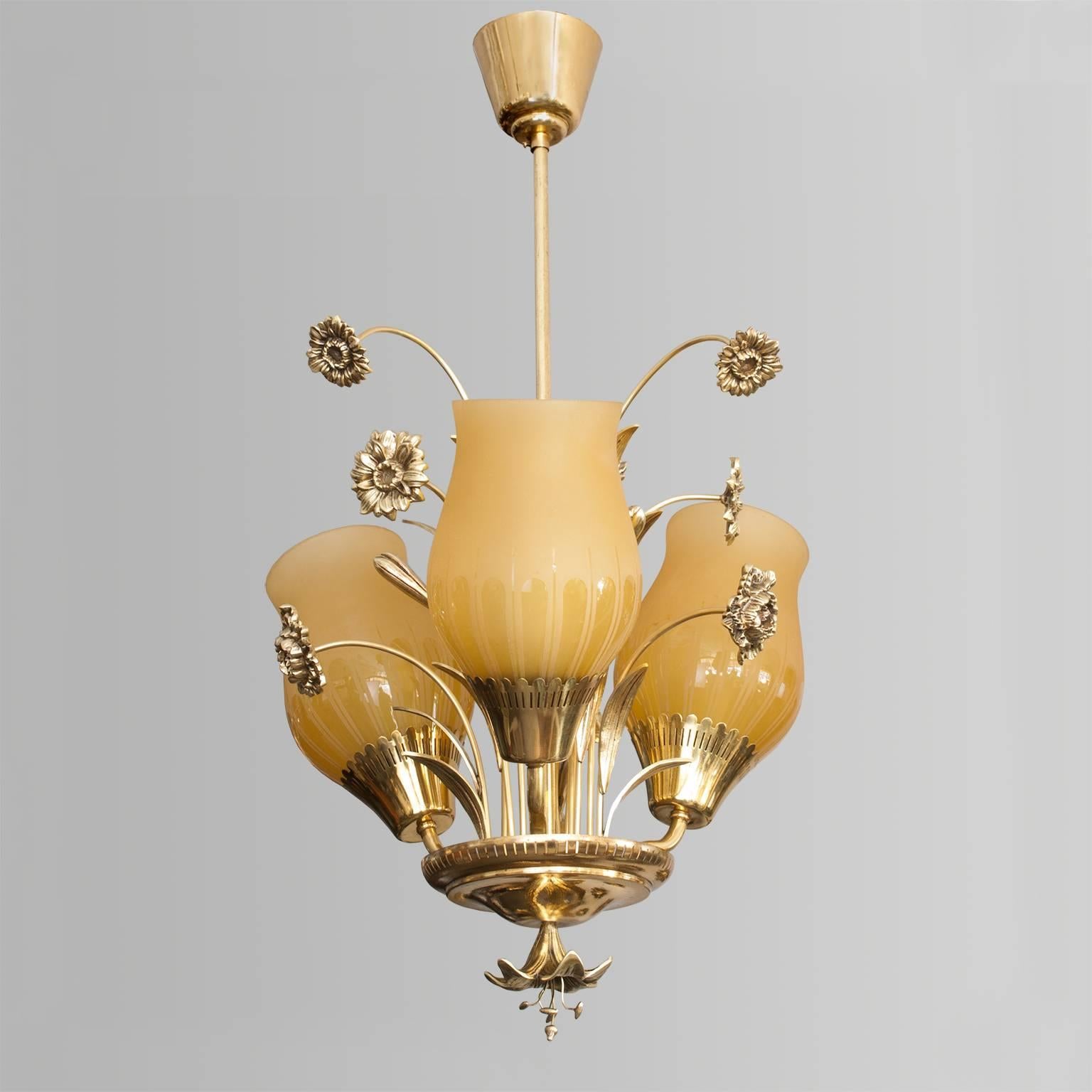 A delightful Scandinavian Modern, Mid-Century, polished brass and bronze pendant with three etched glass shades. The pendant features stems of flowers, leaves and reeds from the center body. A flower finial sits below a pierced brass disk. The