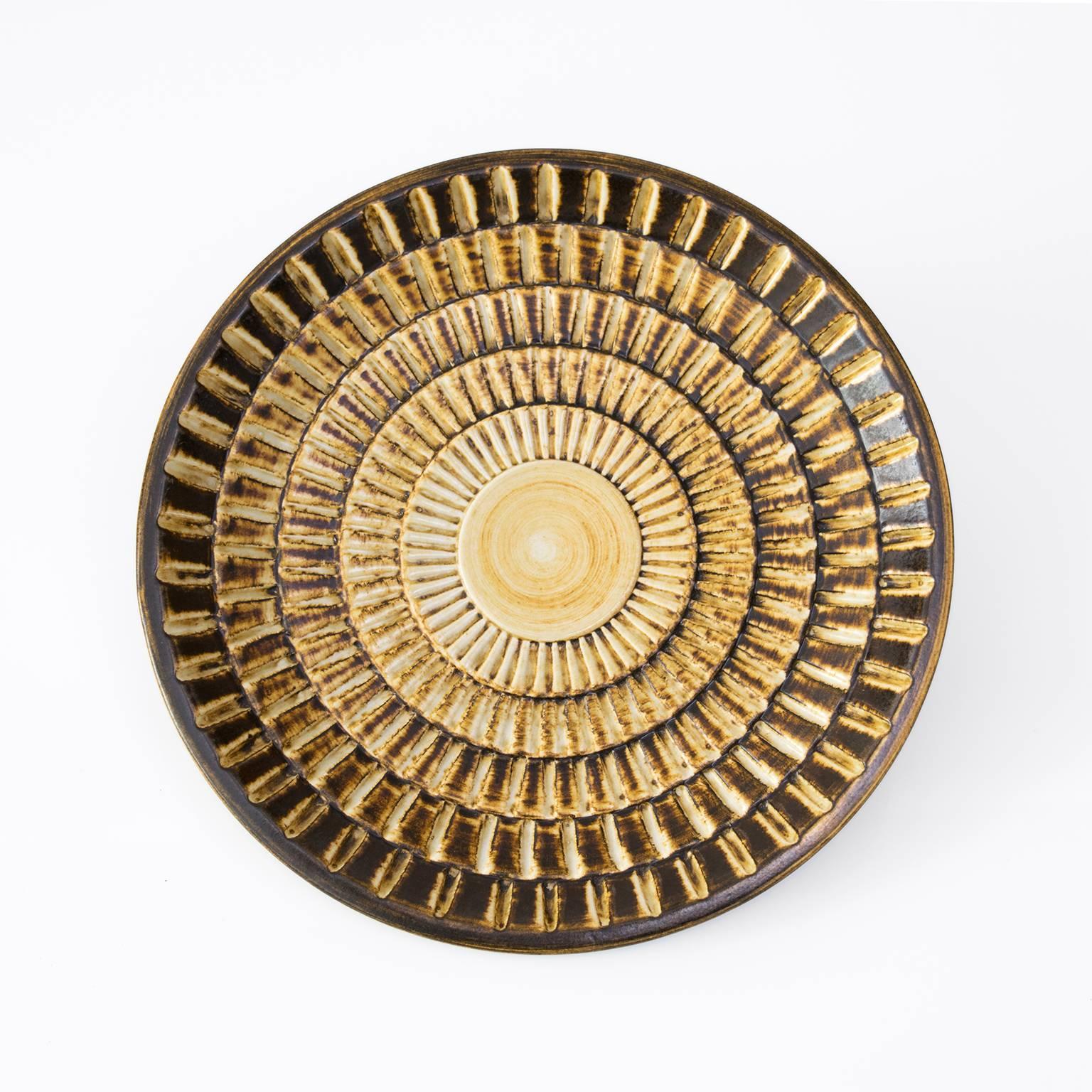 Scandinavian modern ceramic shallow bowl by Gertrud Lonegren in golden glaze and a highly textured surface. Diameter: 11.25