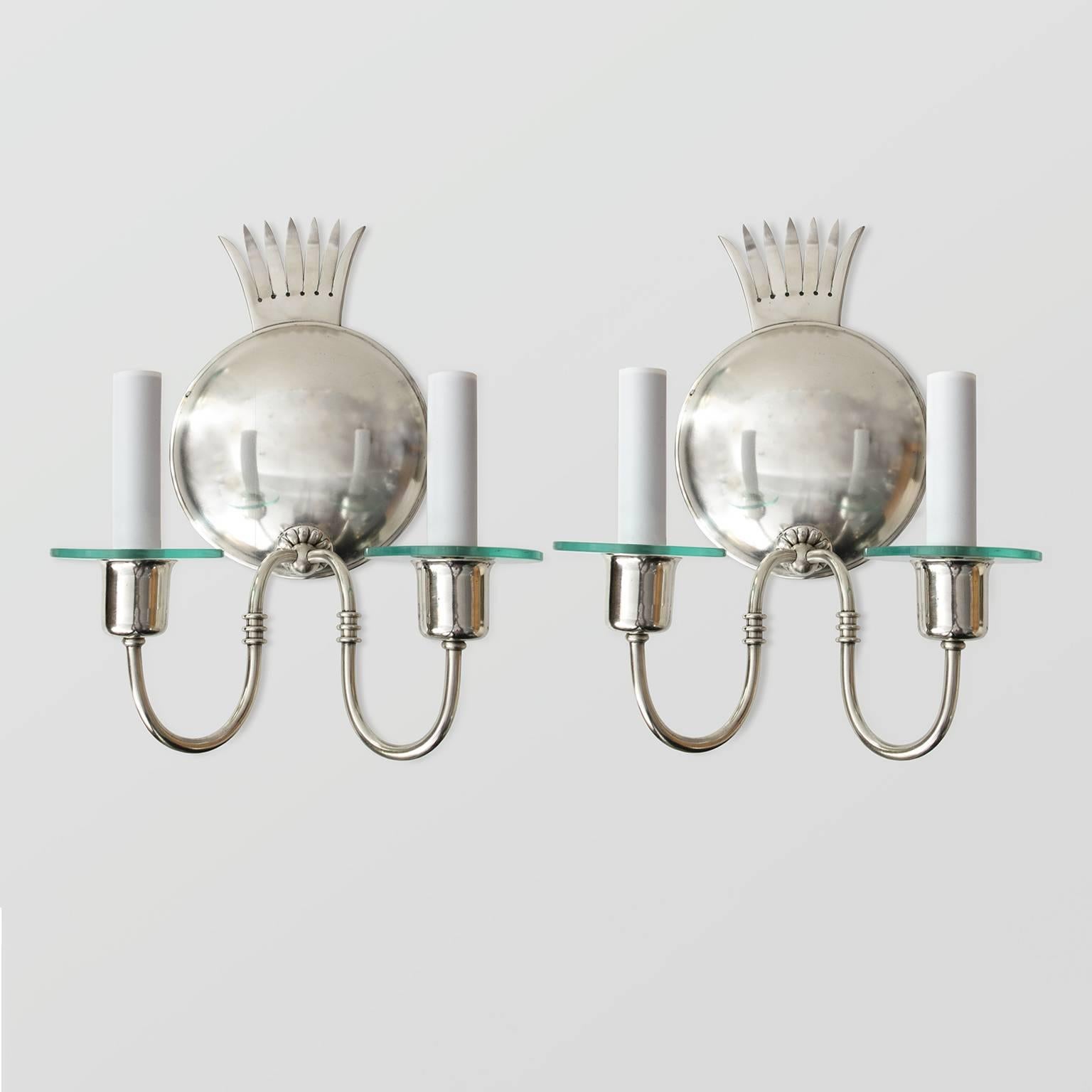 Elegant pair of Scandinavian Modern two-arm silver plated sconces by Elis Bergh for C.G. Hallberg. Each sconces has a round convex backplate with a stylized crown at the top. Each arm is detailed with a custom glass bobeche. Newly polished and