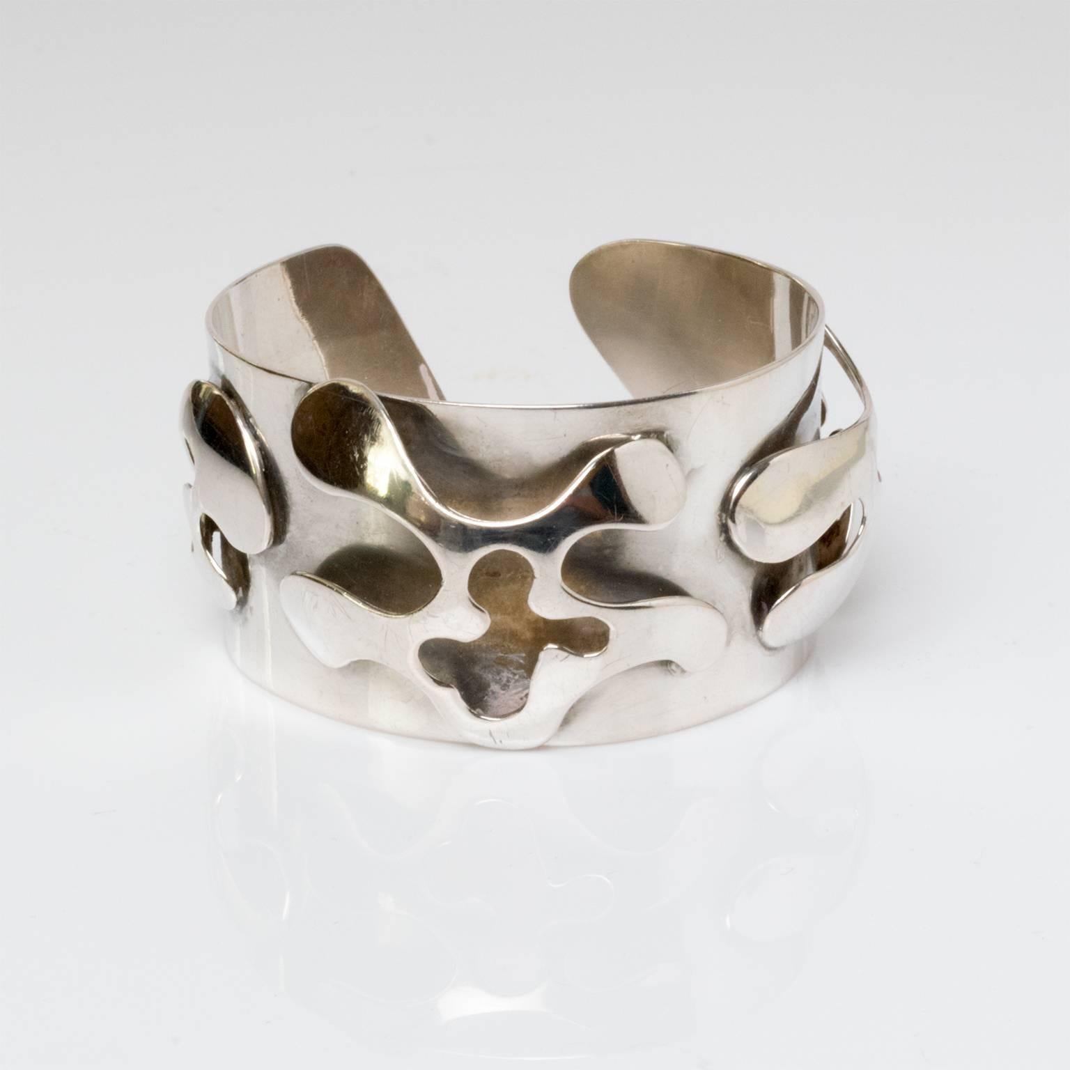 A Scandinavian modern silver bracelet with a raised cutout surface with free-form organic shapes. Designed Henry Marius Jacobsen, Copenhagen, 1960, Denmark.
Measures: Diameter: 2.5".
Height: 1.5".