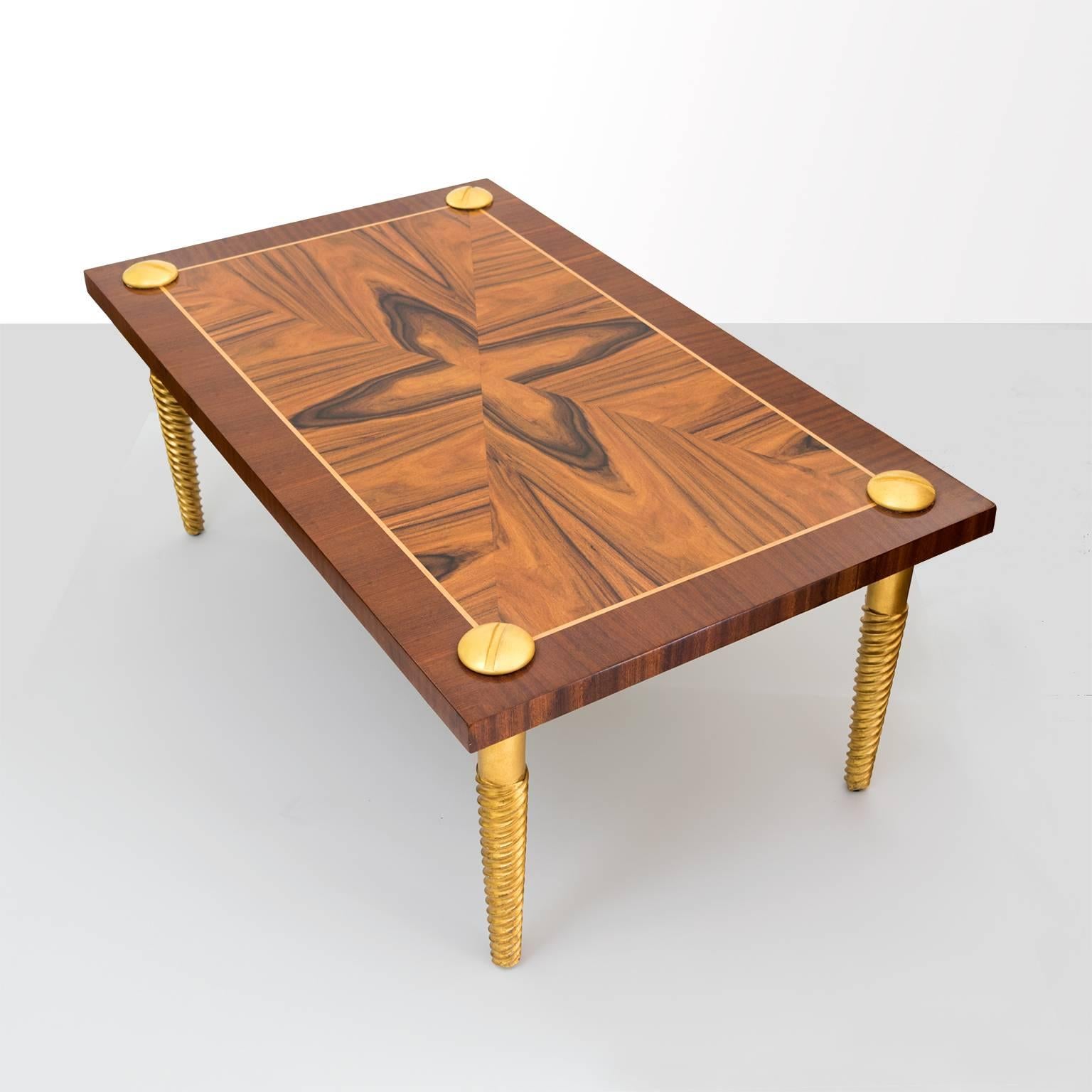 Midcentury Modern European walnut and mahogany marquetry coffee table. The legs are gilt carved wood in the form of screws with screw heads on the surface. Newly restored in excellent condition.

Measures: Length 47.25