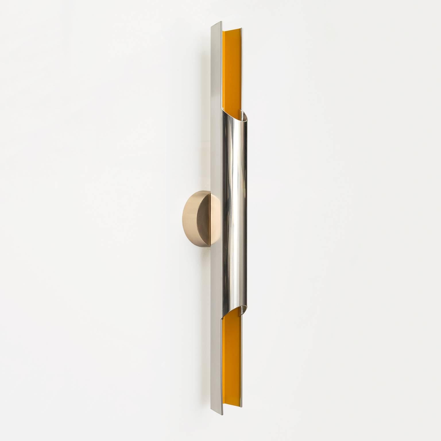 A Scandinavian Modern "Pan-Opticon" sconce in polished aluminium with yellow lacquer. Designed by Bent Karlby for Lyfa, Denmark, 1968. The tubular form hold two candelabra base sockets. The backplate is polished brass. Newly rewired for