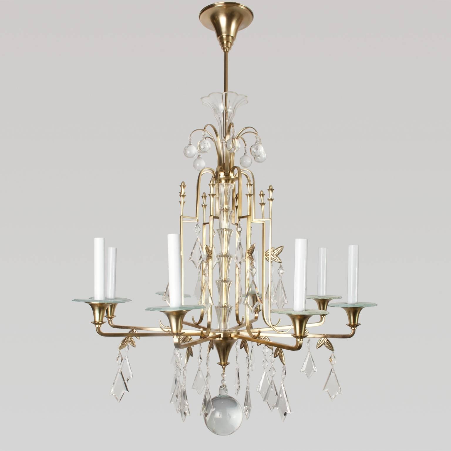 Fine Swedish Art Deco polished brass, eight-arm chandelier. The chandelier is in the form of a fountain with levels of crystals. The center stem has a stepped glass sleeve which follows to the canopy. A large solid glass crystal sphere is suspended