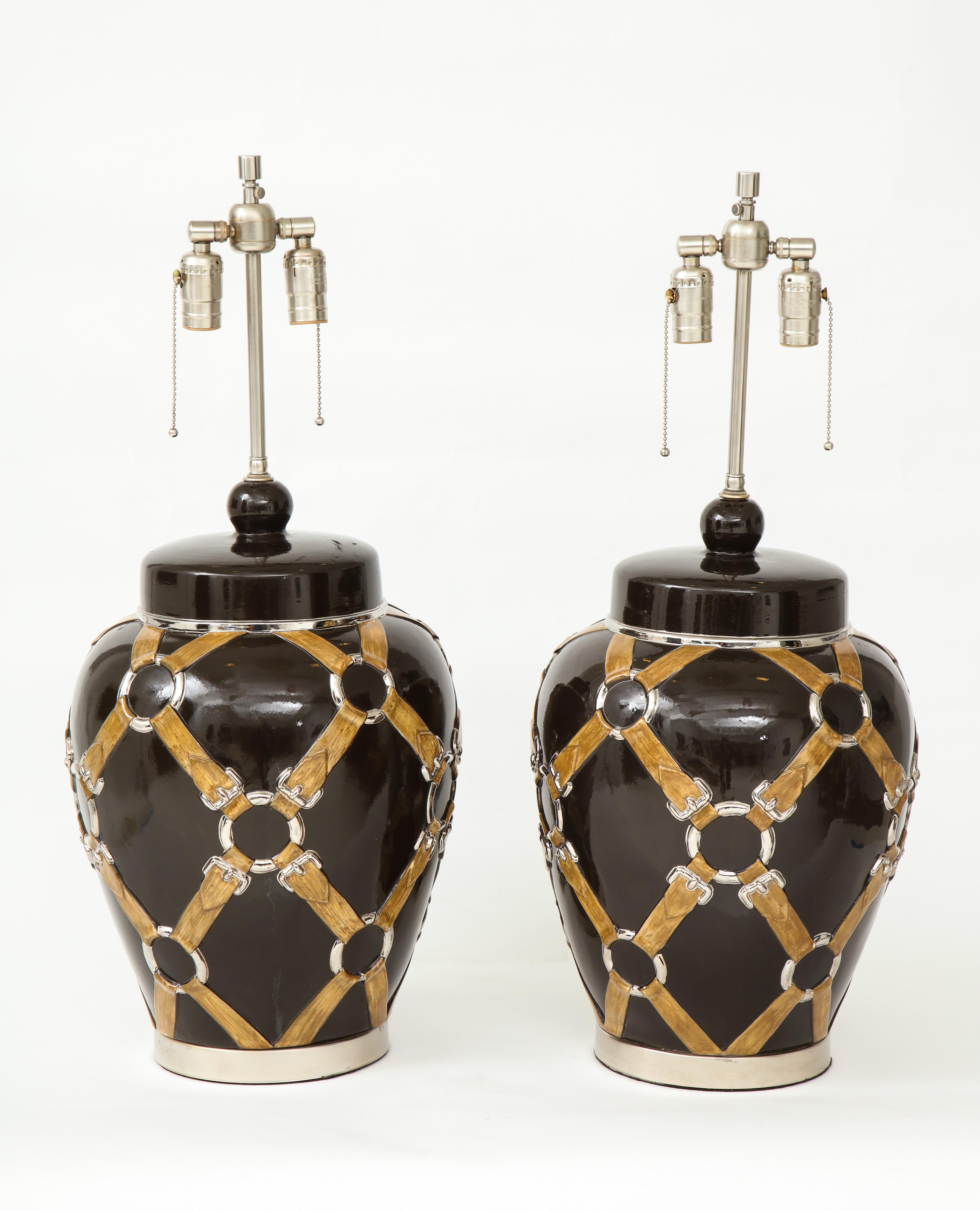 Exquisite pair of Gucci inspired brown glazed ceramic lamps with ginger jar shaped bodies with stylized straps and buckles sitting on brushed nickel bases. Rewired for use in USA. 100W max, unless LED bulbs.