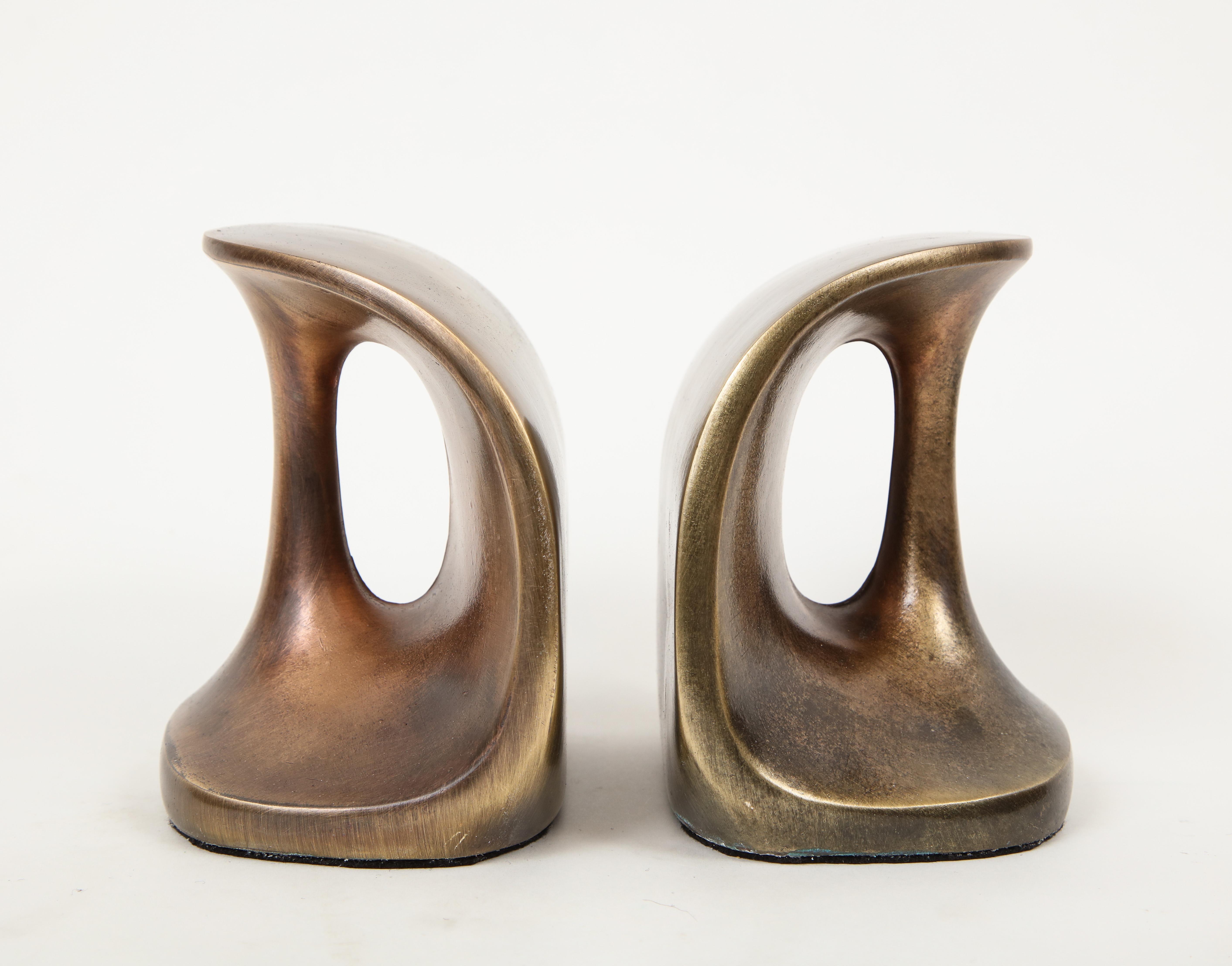 Pair of modernist bronze bookends featuring seductive curves and open handles.