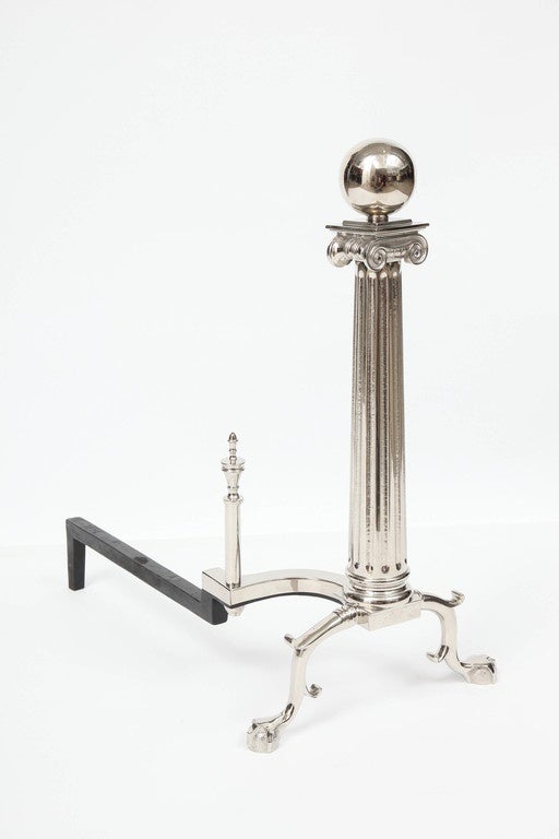 Stately pair of neoclassical style andirons with cannon ball tops and column bodies in polished nickel. The classic, timeless form of this pair lend themselves to multiple interiors.
