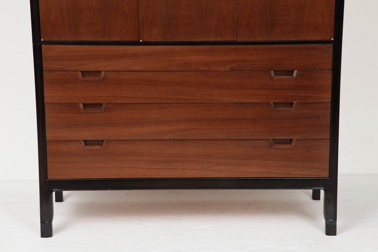 Midcentury Classic chest of drawers featuring an ebonized walnut case with contrasting dark brown stained walnut drawer/door fronts. Chest has four ample drawers and three compartments with shelves which perfectly houses folded shirts and sweaters.