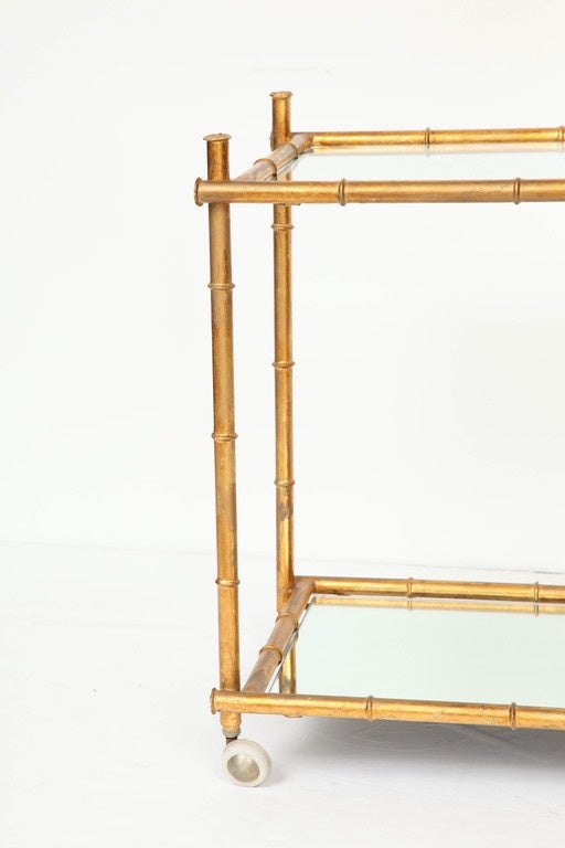 Mid-Century Italian gilt metal serving/bar cart with a stylized bamboo frame and  glass and mirror shelves. 