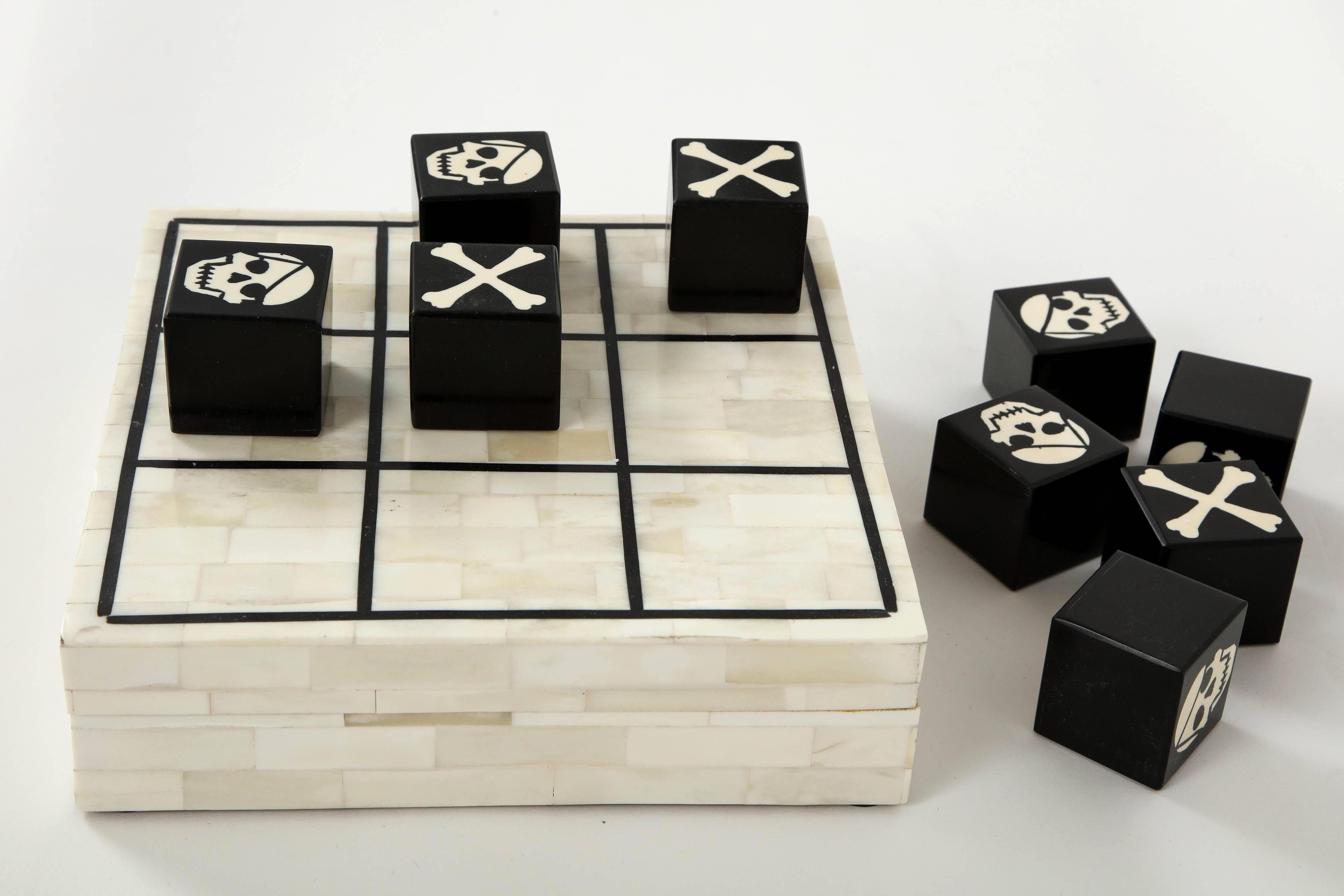 Stylish Tic Tac Toe game made from natural and dyed bone inlay. Game pieces feature skull and cross bones. Game board opens to store game pieces. A great addition to any coffee table, desk or bookcase.