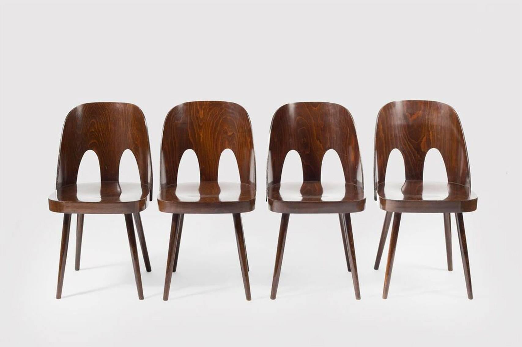 Four dining chairs by Oswald Haerdtl designed for Thonet. Chairs are made out of beech wood, stained and lacquered in high gloss finish. Bent wood swooping backs have two openings.