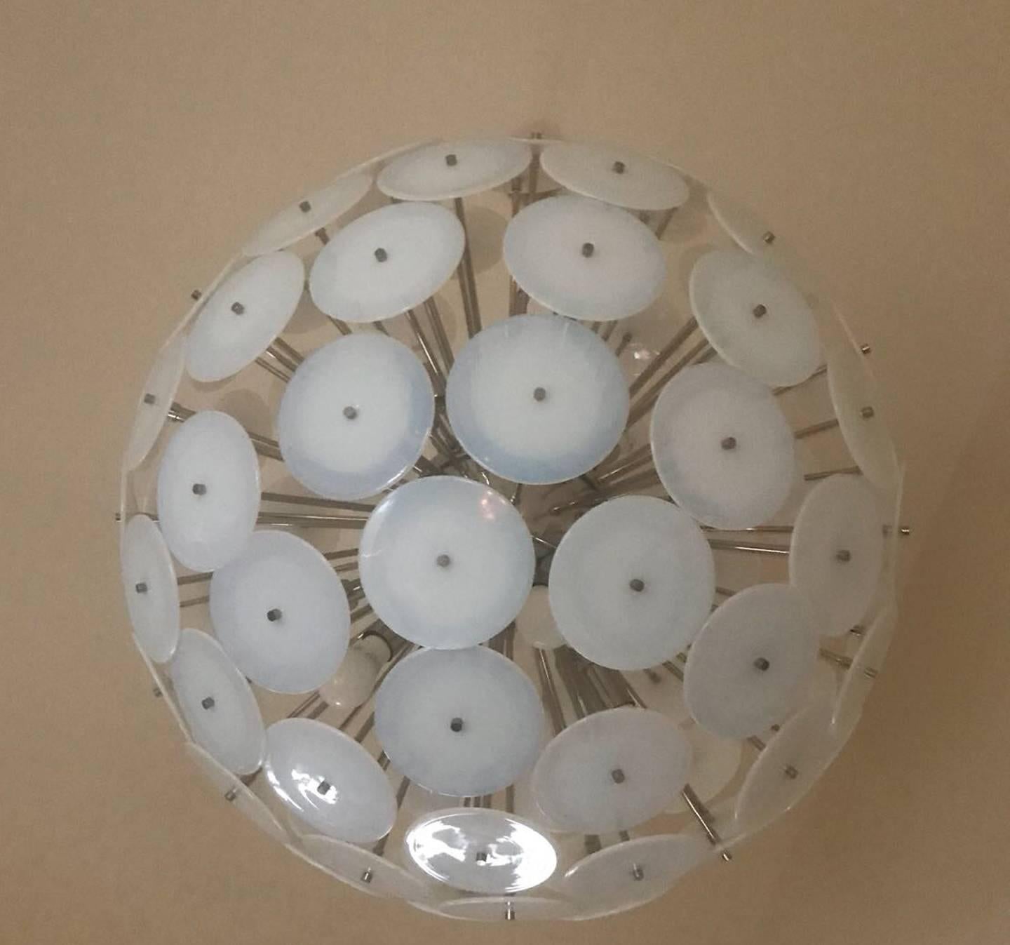 Huge iridescent glass chandelier. Chrome-plated steel structure with 95 round Murano, white glass disks. Each disk is 6 inches in diameter, 12 light sockets branching out of the center globe. There is a chain which lengths can be adjusted to your