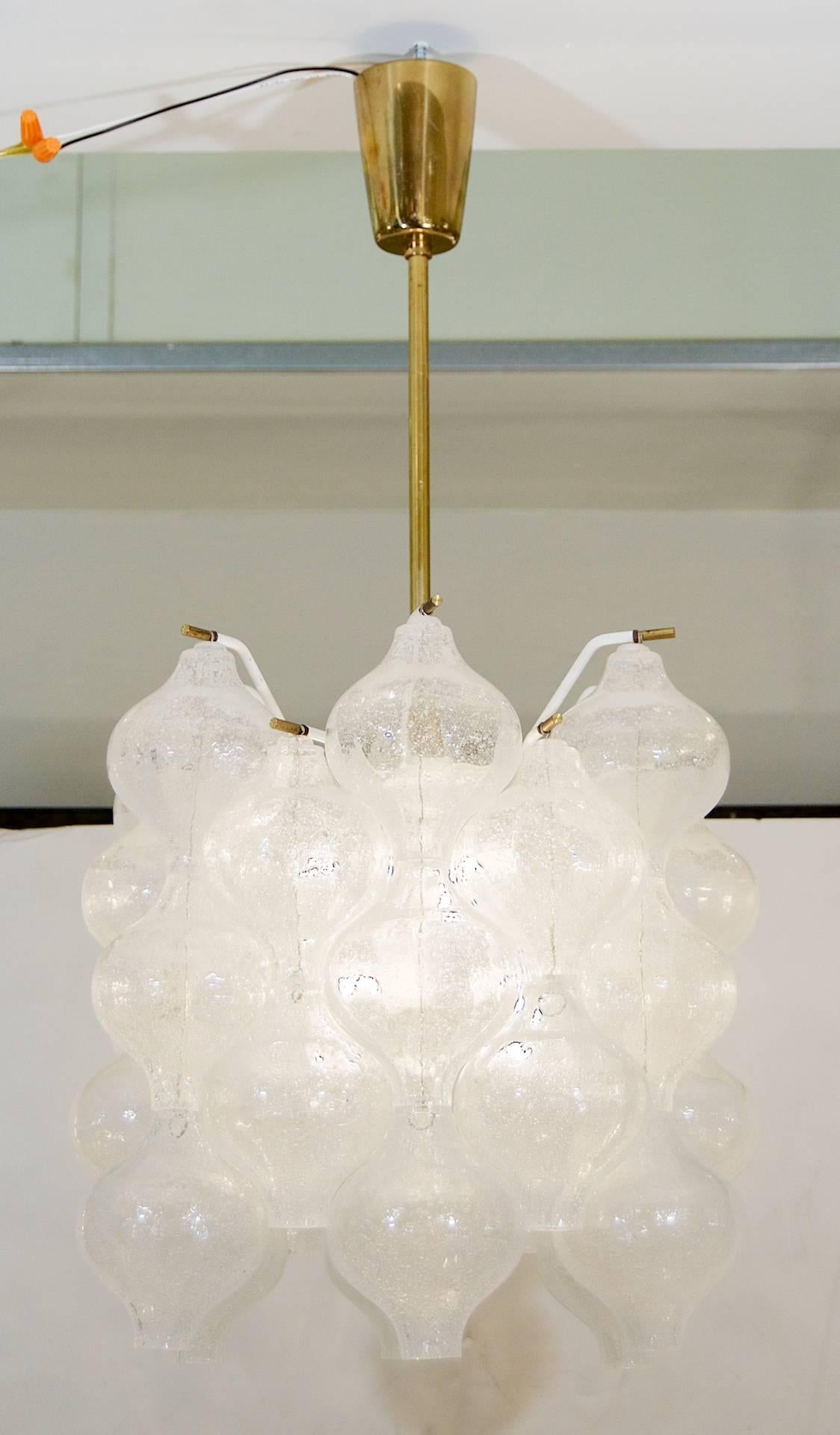 An excellent Kalmar Tulipan glass pattern chandelier, having 31 individually hung pieces of glass in 12 vertically stacked chains. Each piece of handblown glass is wire suspended on brass pins, with the central body in enameled white.

Six E-14