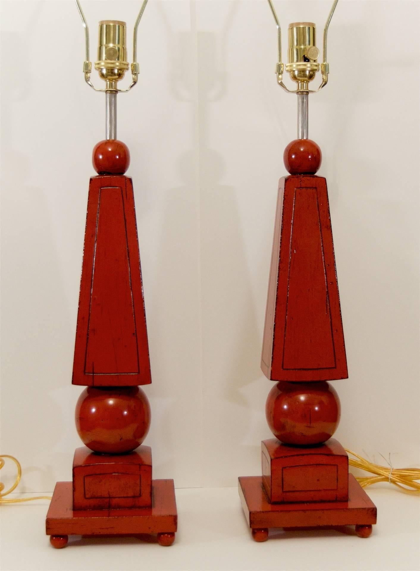 Excellent pair of wood obelisk form table lamps, lacquered in oxblood red with antiquing.

New wiring and three-way medium base switches up to 150 watts.

Height listed is with 10