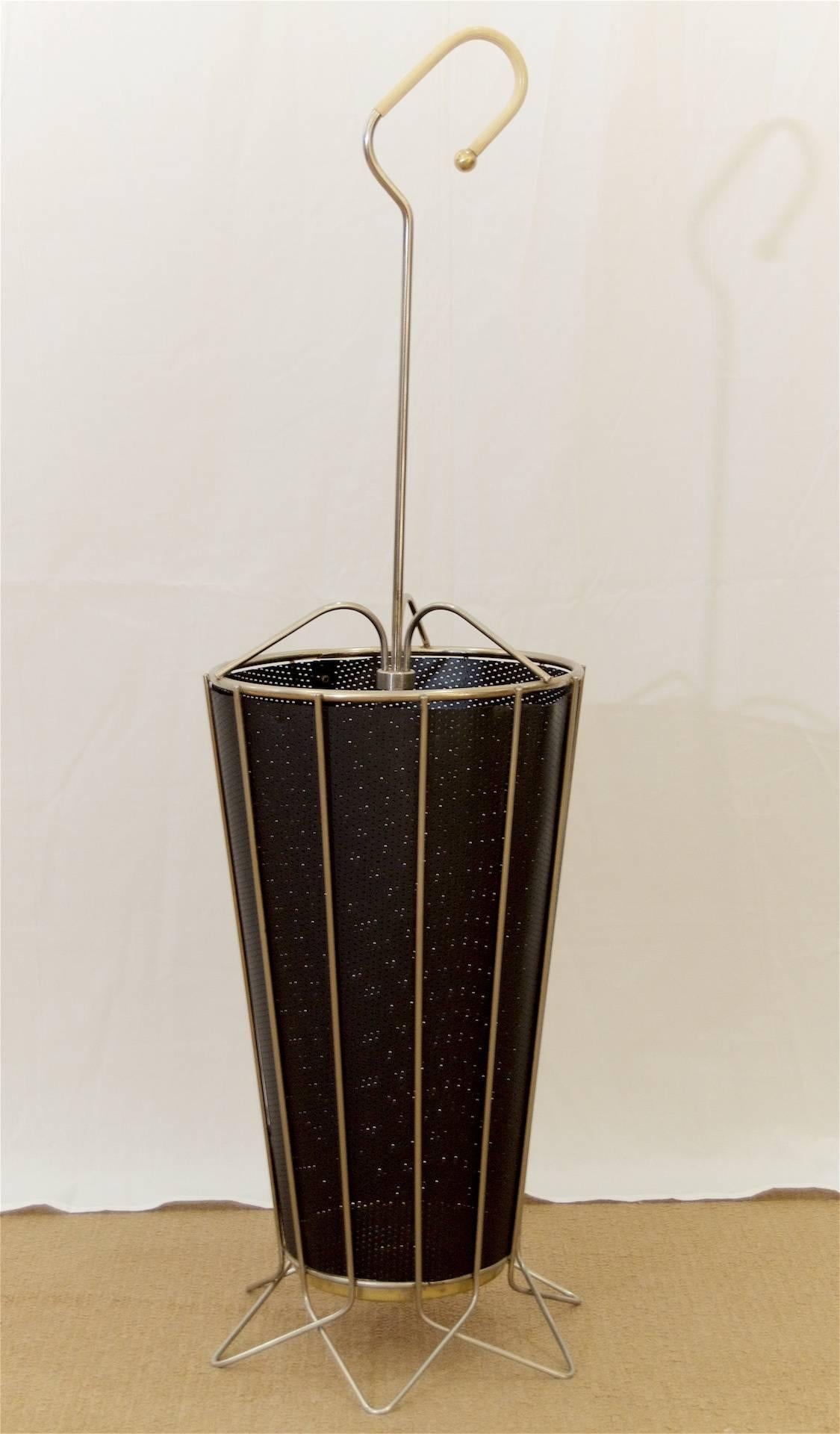 Well-sized umbrella stand, the body of steel wire (originally brass plated, significant loss to brass finish), sides lined with a perforated black synthetic liner. Brass tray rests in centre of base. 

Height shown is to top of handle. Height to