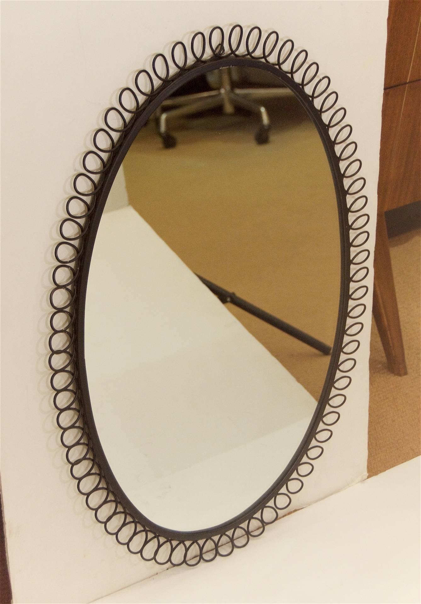 Nicely proportioned mirror in the style of Josef Frank, the oval mirror mounted in a black enameled steel frame with a spiral wire border.
