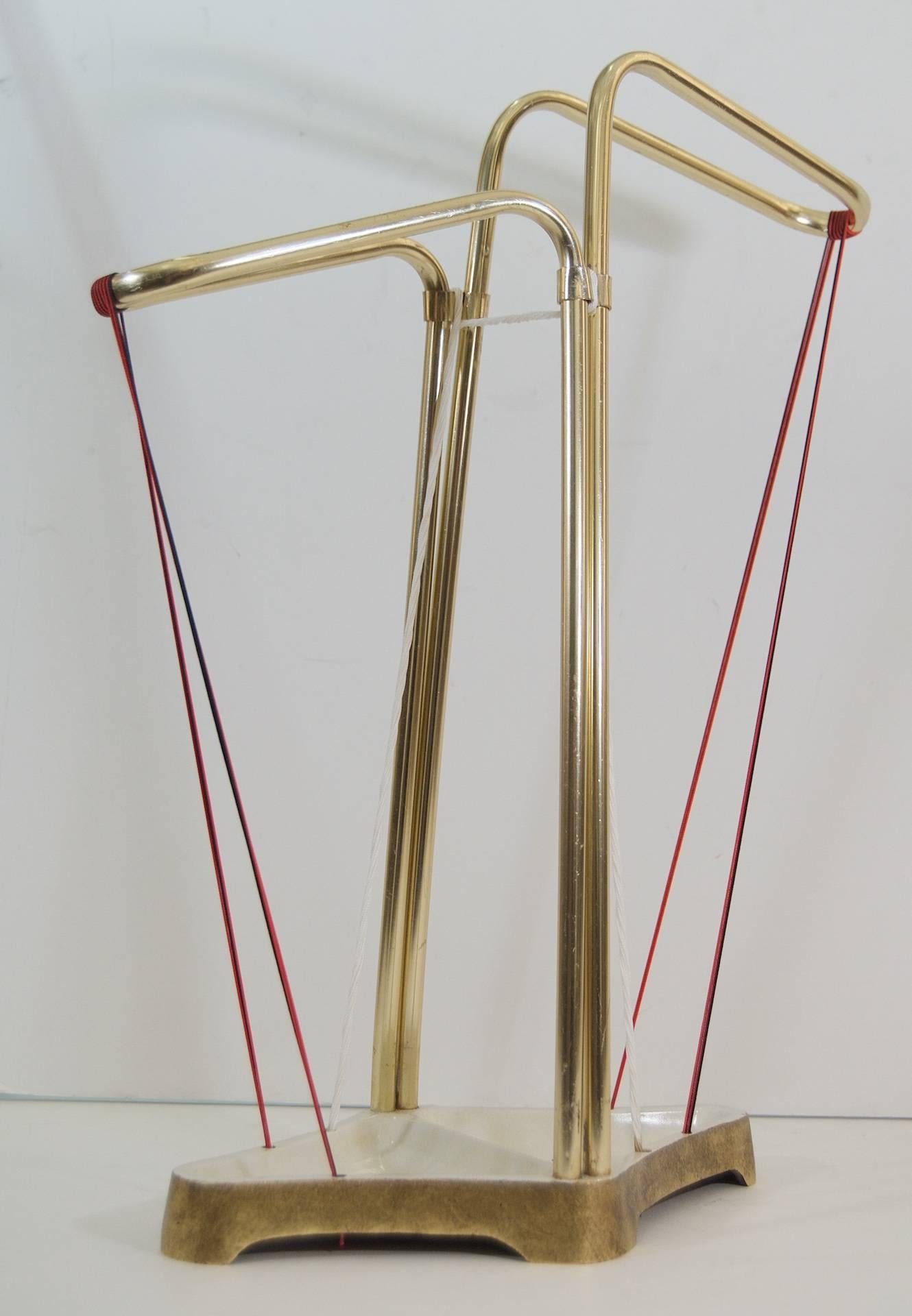 Excellent Mid-Century umbrella stand, the brass arm supports mounted on an enameled and gilt iron base, supported and bound by red, black and white cording.