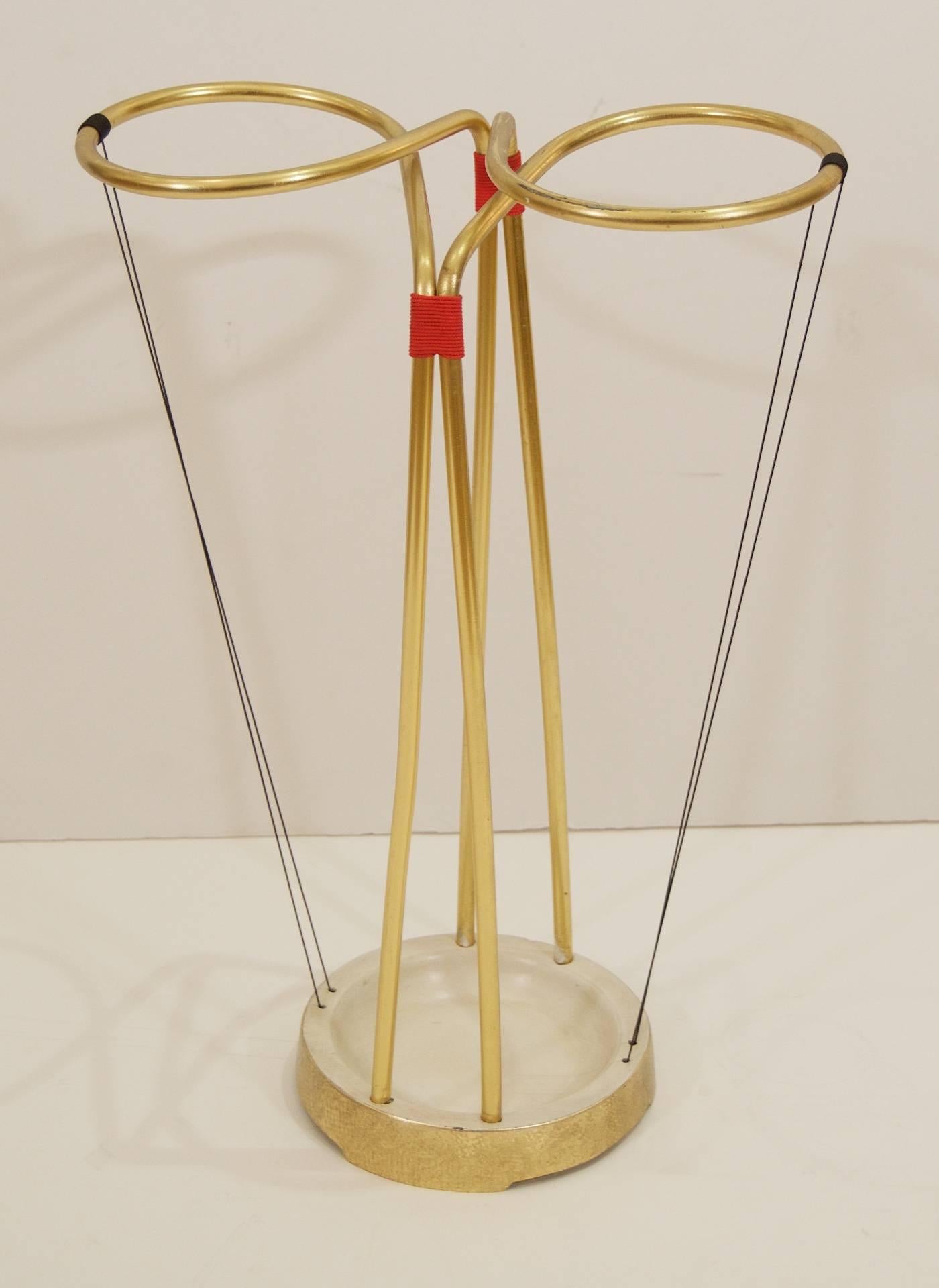 Excellent Mid-Century umbrella stand, the brass arm supports mounted on an enameled and gilt iron base, supported and bound by red and black cording.