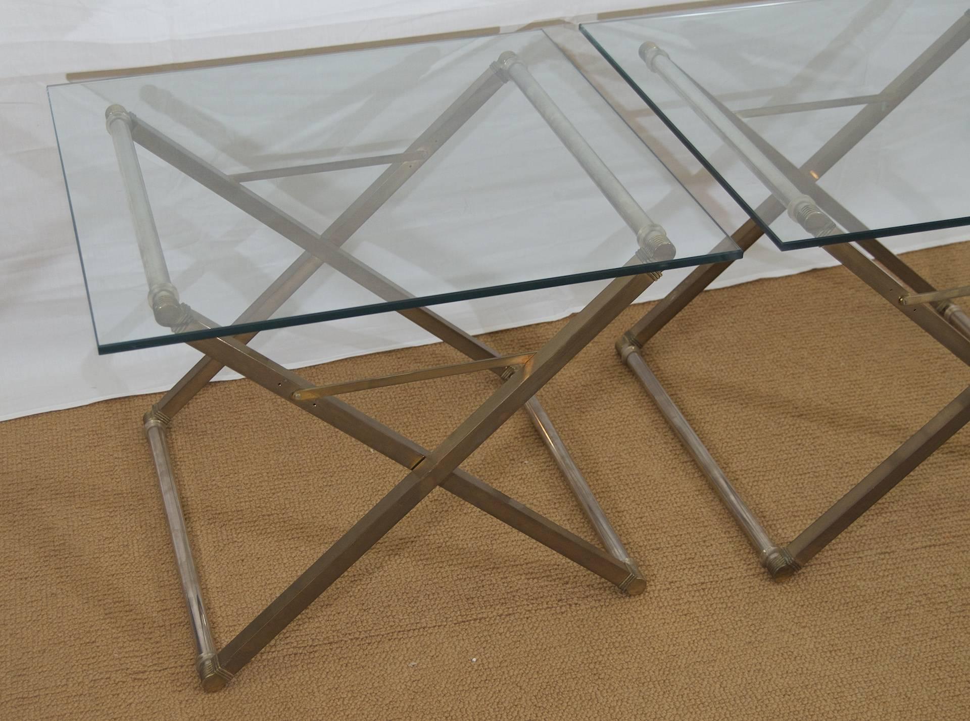 Pair of bronze and steel X-form based tables with a square glass top.

Please note the height of the tables is adjustable by screw-fitted cross brace. Height listed is middle height setting. Minimum height is 13.25 inches and maximum is 18.25