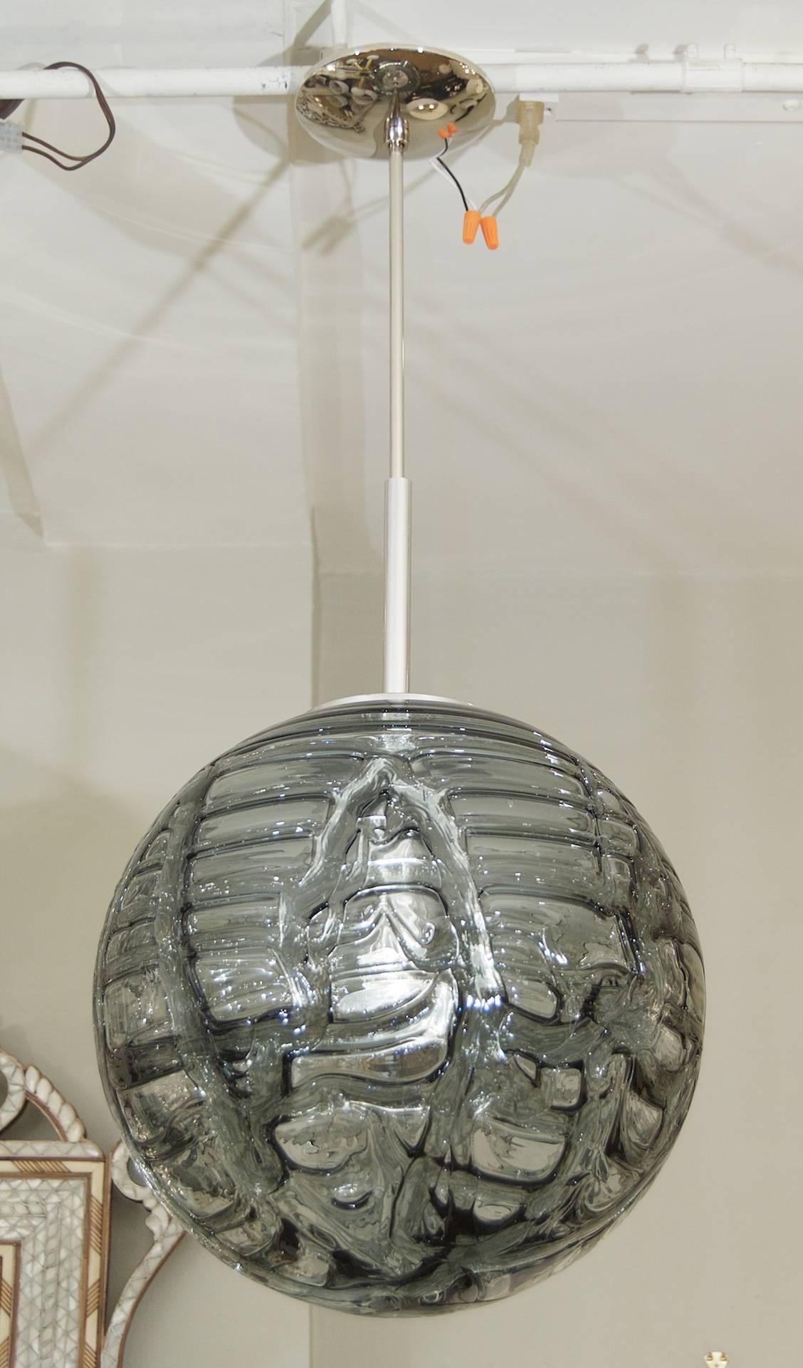 Fantastic Doria pendant will complement all decors. Heavy textured wave surface glass, smoke tones variegated from clear.

Chrome hardware.

Takes a single medium base bulb up to 100 watts, new wiring. Length of drop rod can be adjusted. Height