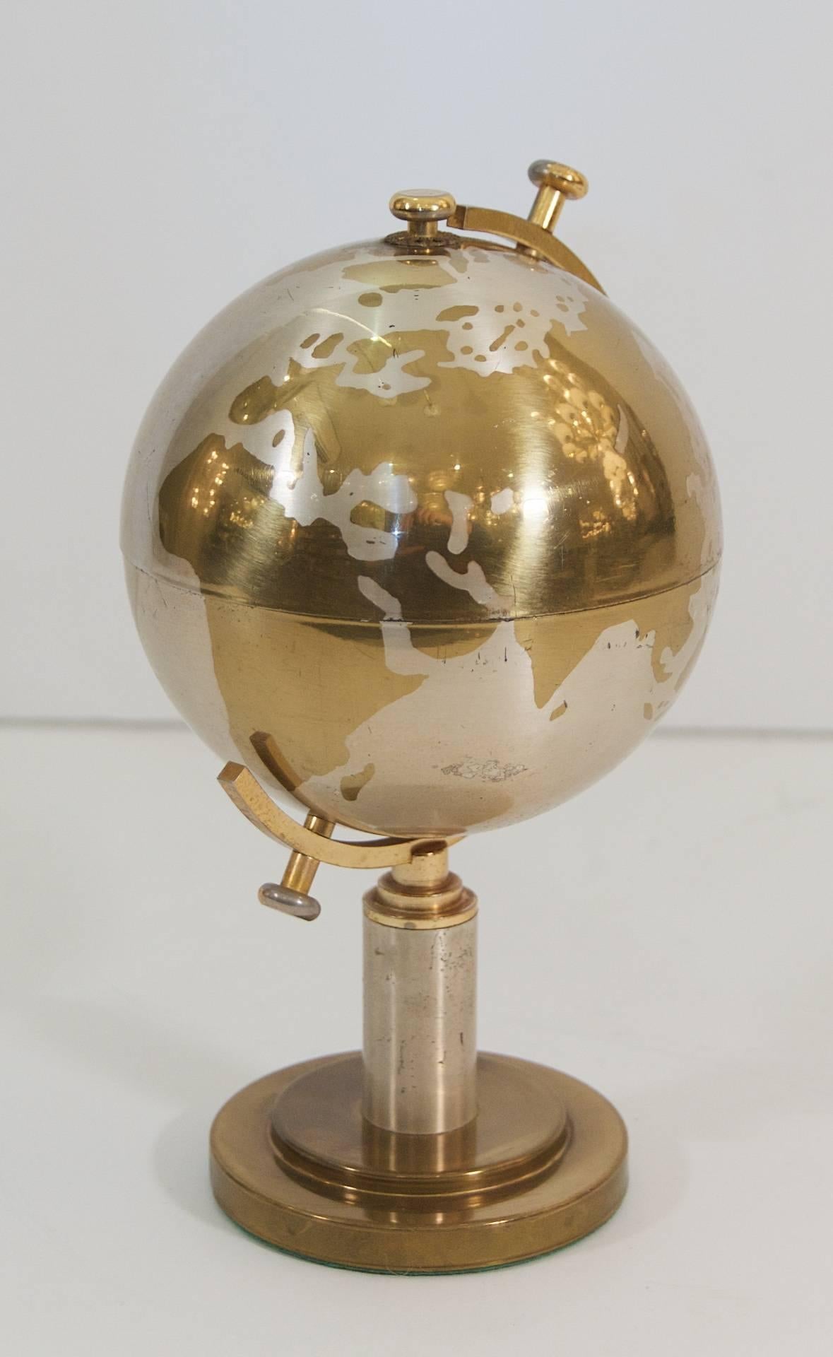 Unique steel and brass cigarette holder, the globe opens to display individual vessels for cigarettes.