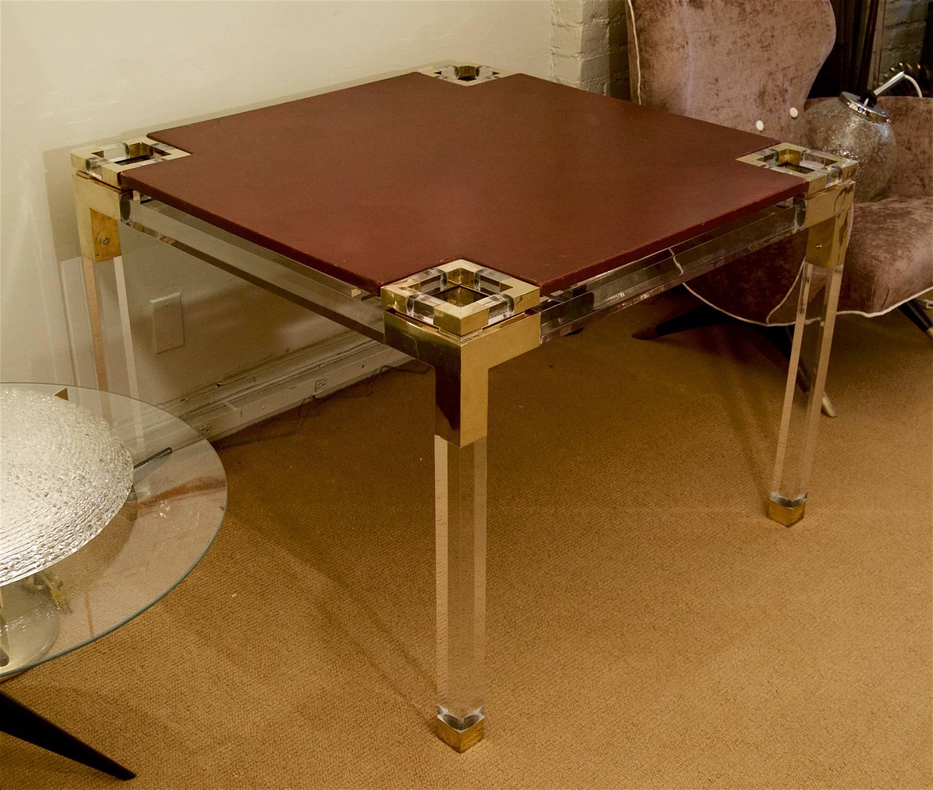 An incredibly unique Lucite card table with brass hardware joinery and a removable oxblood tone leather top.

Corner coasters are removable.