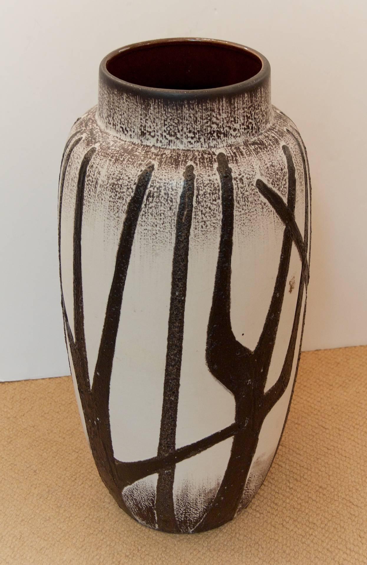 A well sized vase made by Scheurich Keramik. Layering of matte brown glaze underneath a cream semi gloss leaving tree form shapes. Would also serve as an umbrella stand.

Opening is 6 inches. Please see other listings for other patterns and sizes.