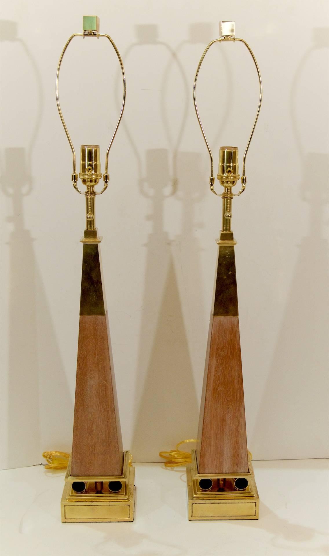 Wood Obelisk form table lamps with brass accents attributed to Tony Parzinger, manufactured by Stiffel Lamps.

Each lamp takes one medium base bulb up to 150 watts per bulb. New wiring. Height listed is to the top of the harp, pictured with an 10
